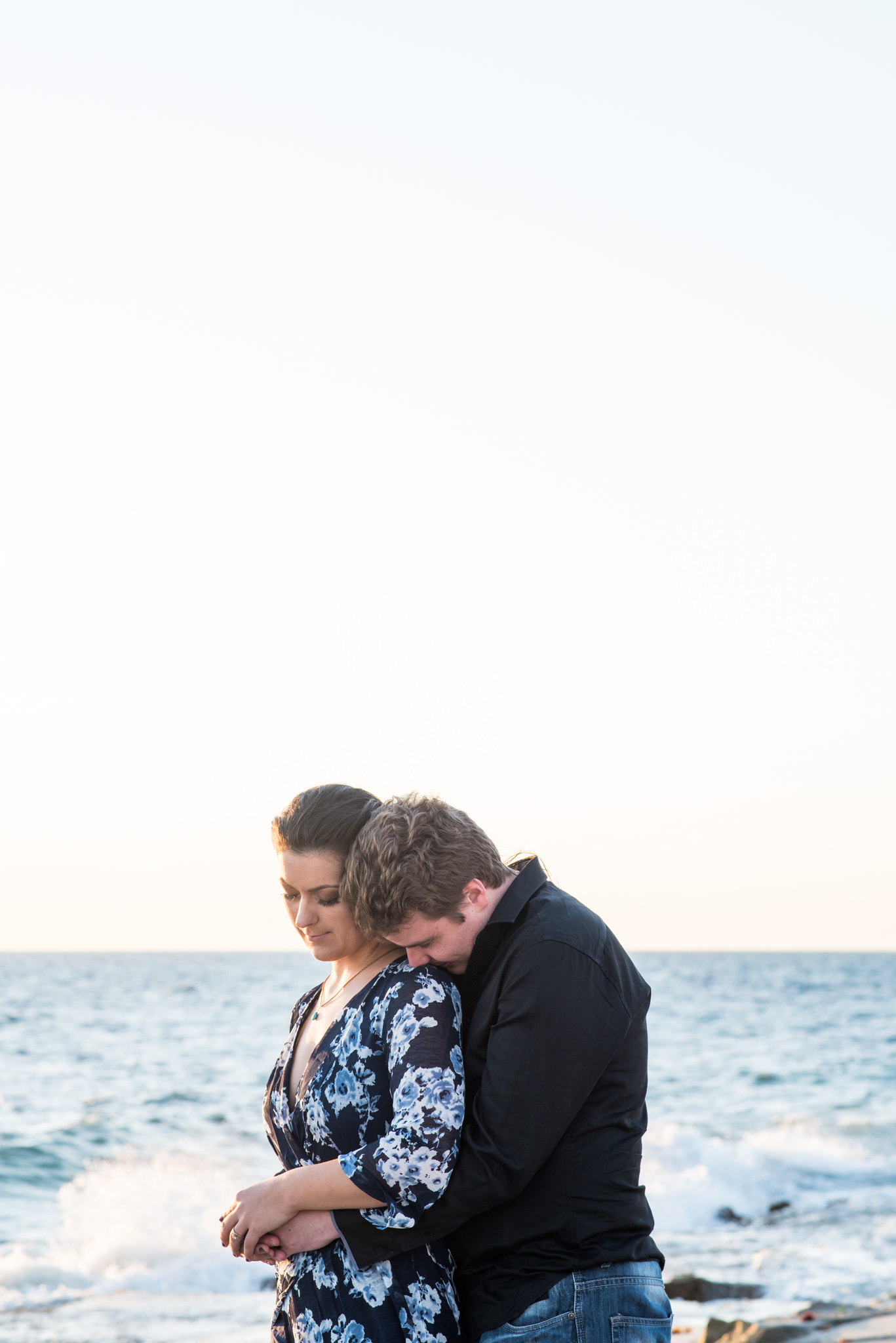 Boy putting nose to girl's shoulder in contemplation at the beach