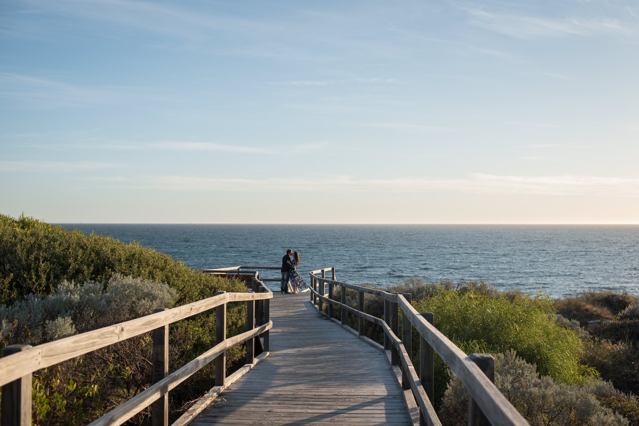 Wide shot of the wooden walkway at Burns beach with couple at the end