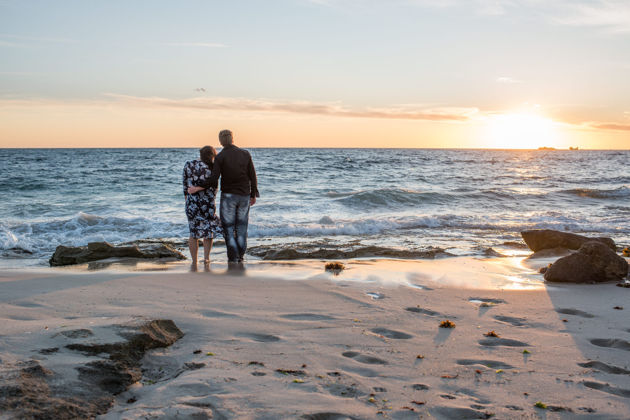 Boy and girl look out over sea at sunset