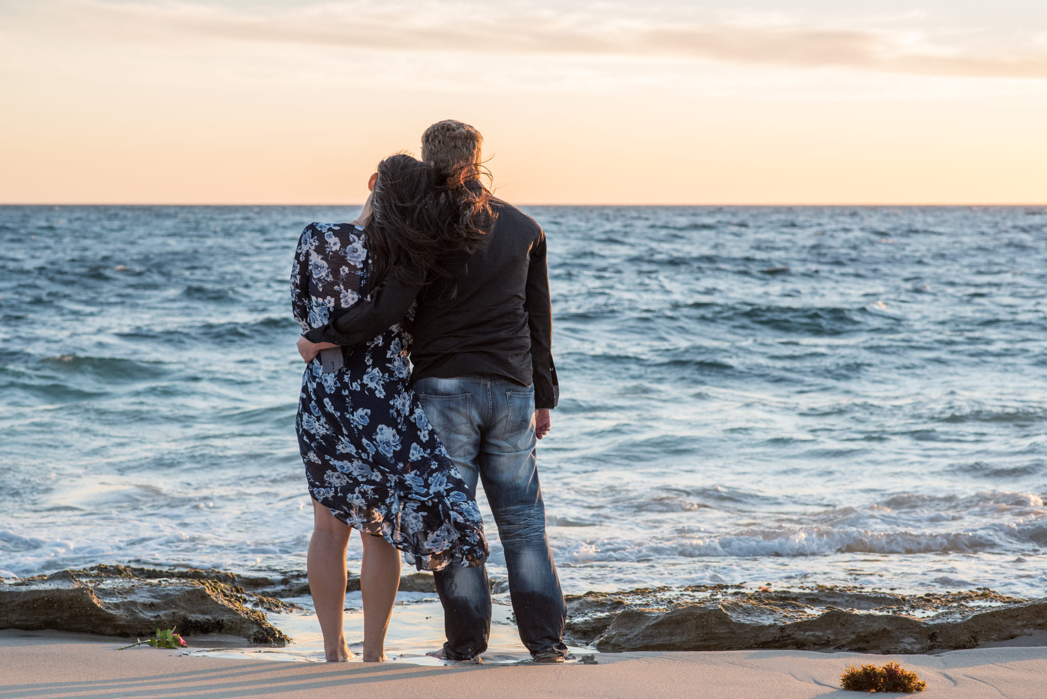 Girl leans head on boy's shoulder watching sunset at Burns beach