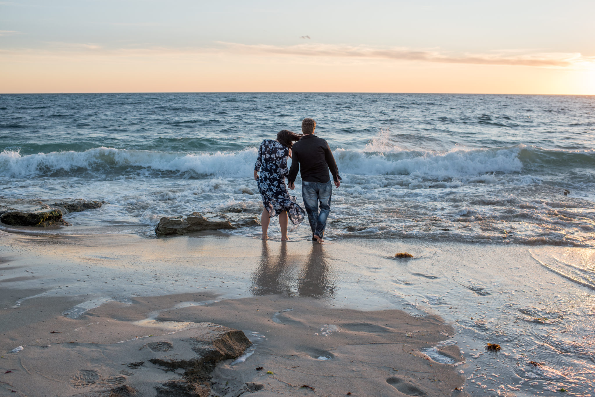 Boy and girl wading in the sea at sunset