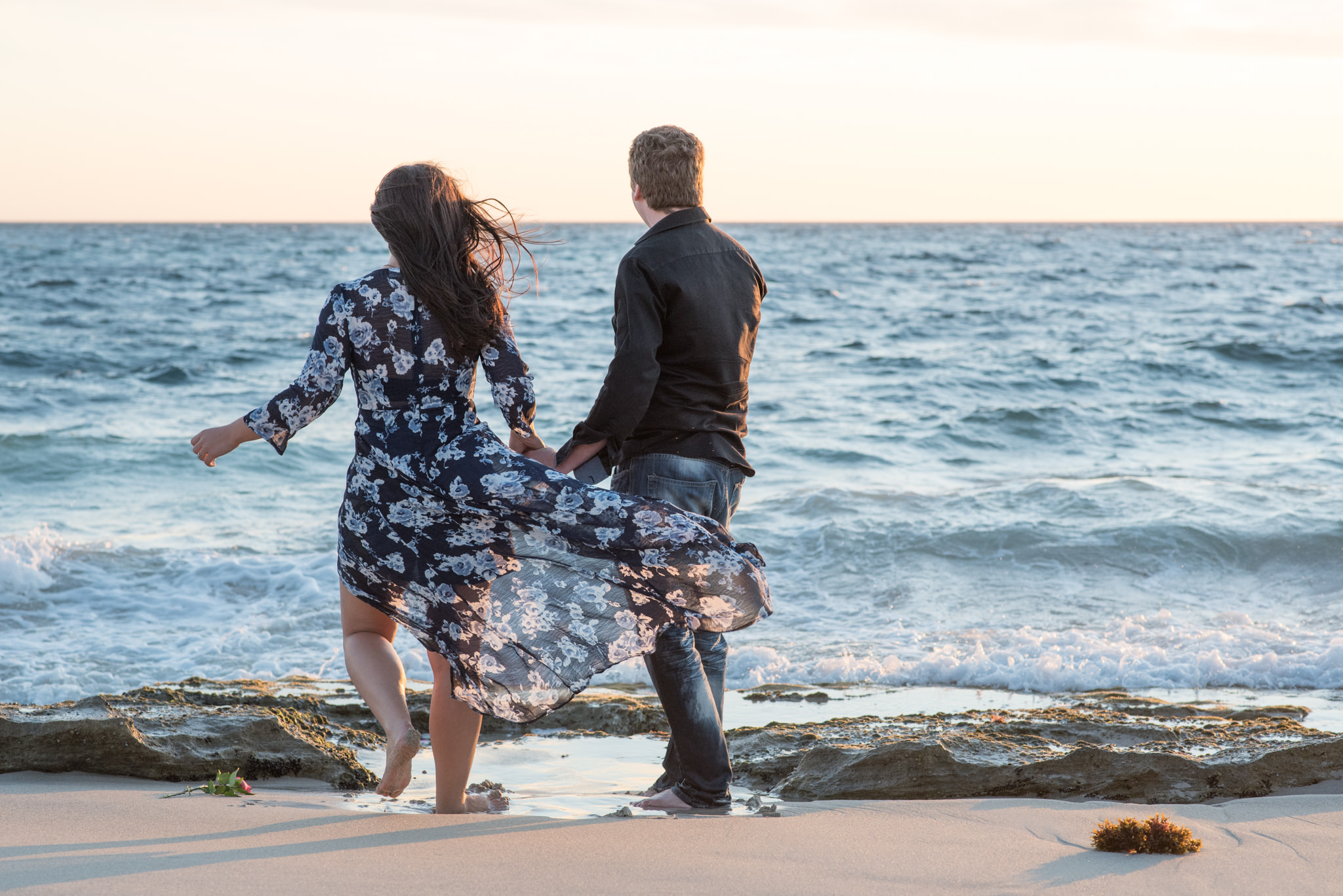 Boy and girl looking out to sea, dress blowing in breeze