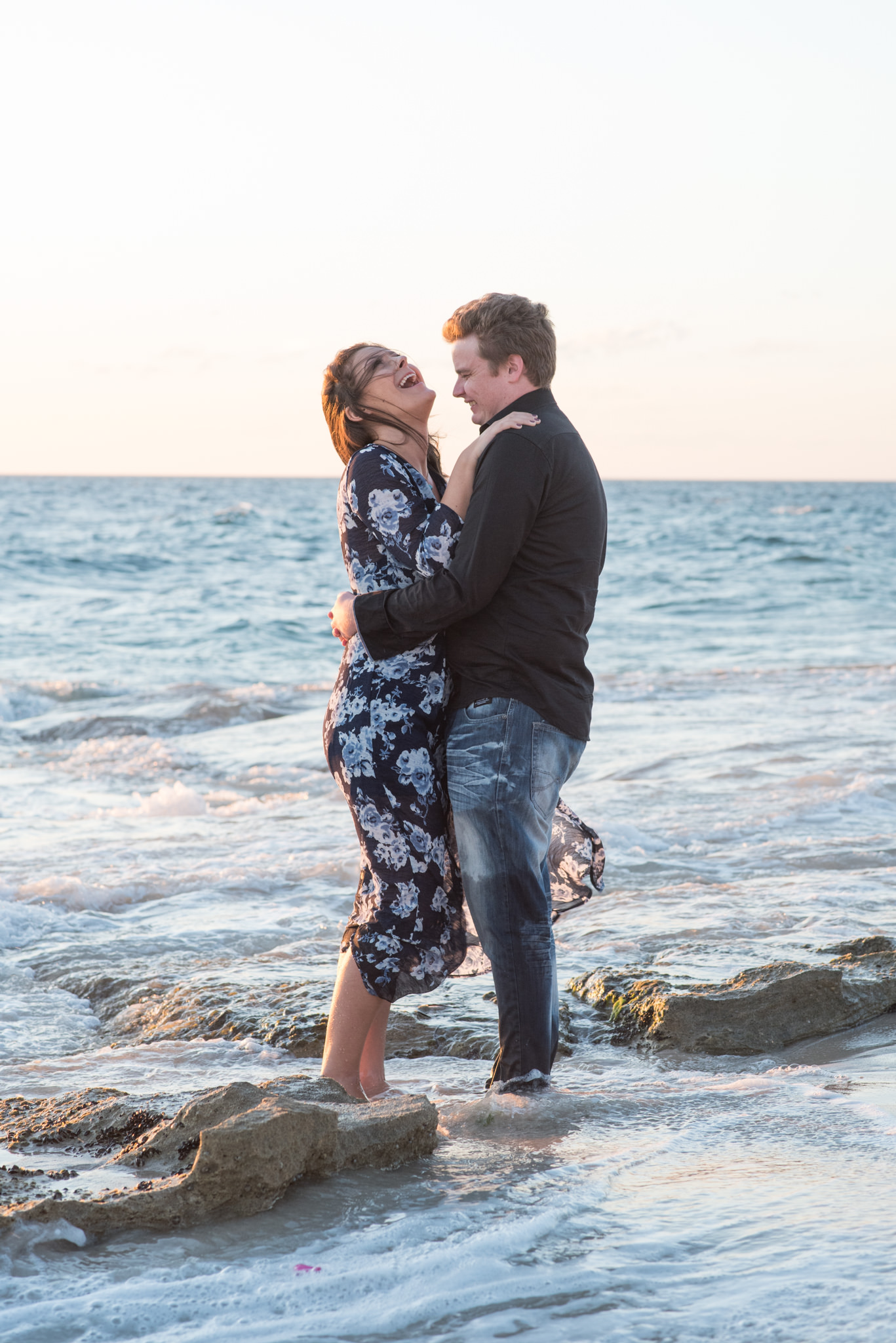 Boy and girl laughing splashing in water at Burns beach