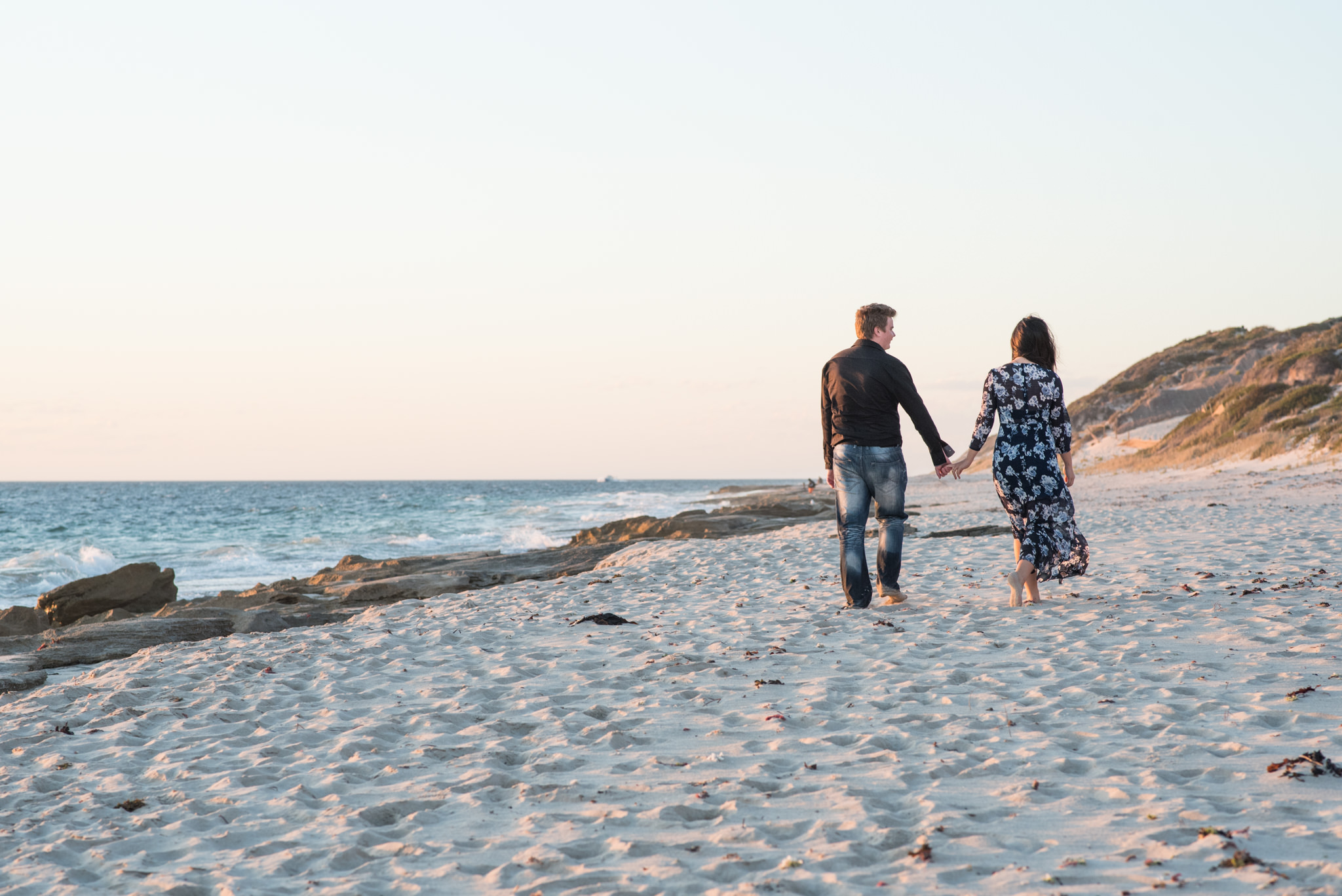 Boy and girl walking away from camera along the beach