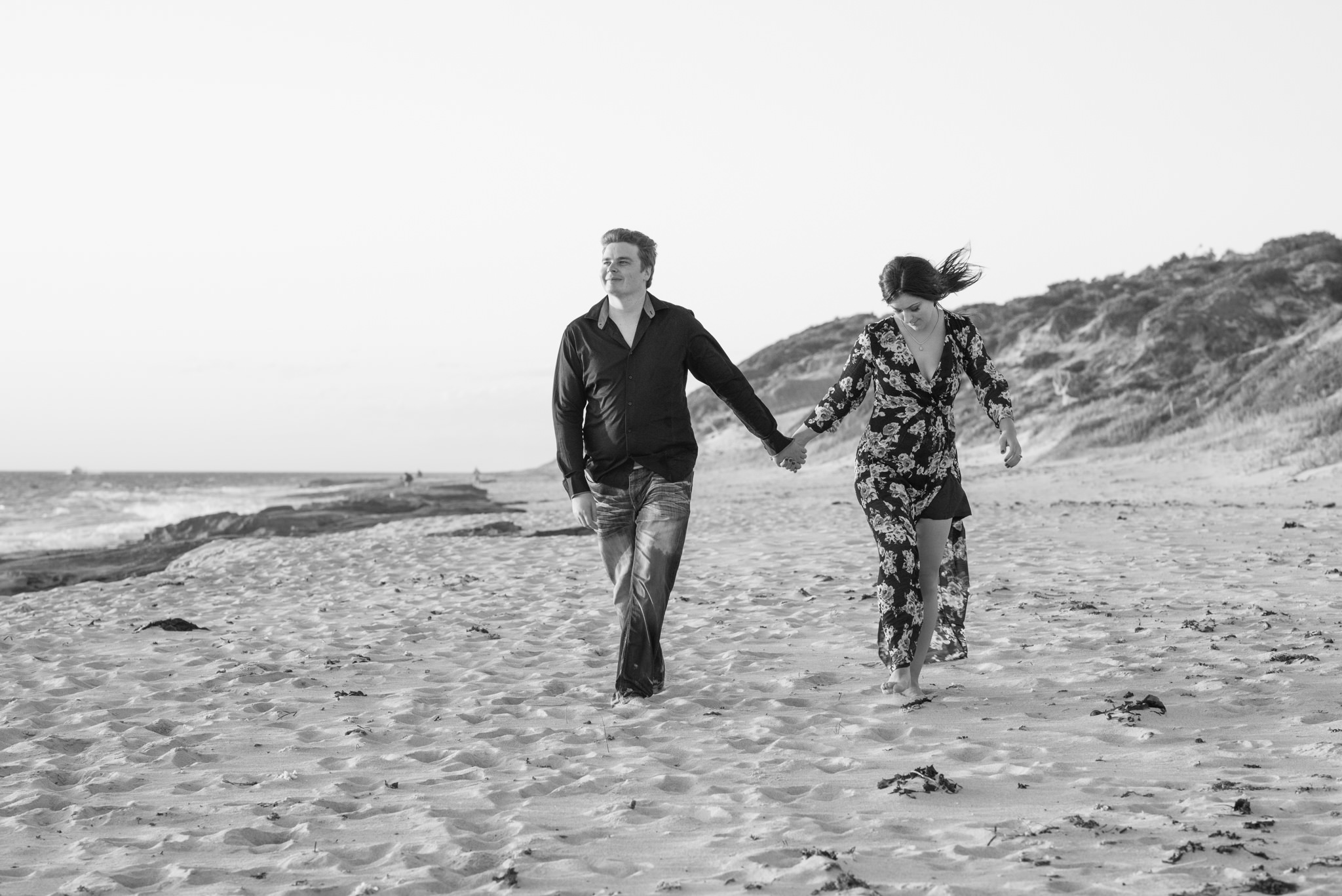 Black and white of boy and girl walking along Burns beach