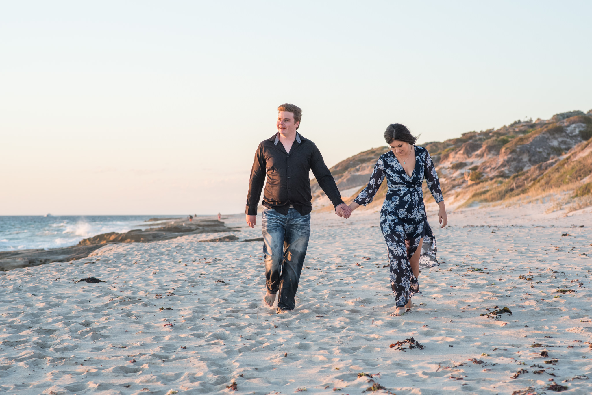 Boy and girl walking along the beach looking out to sea