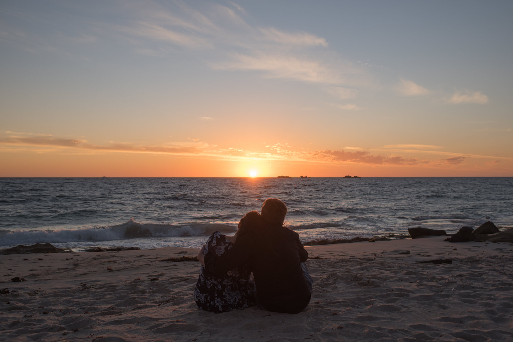 Young couple sitting on Burns beach watching the sunset