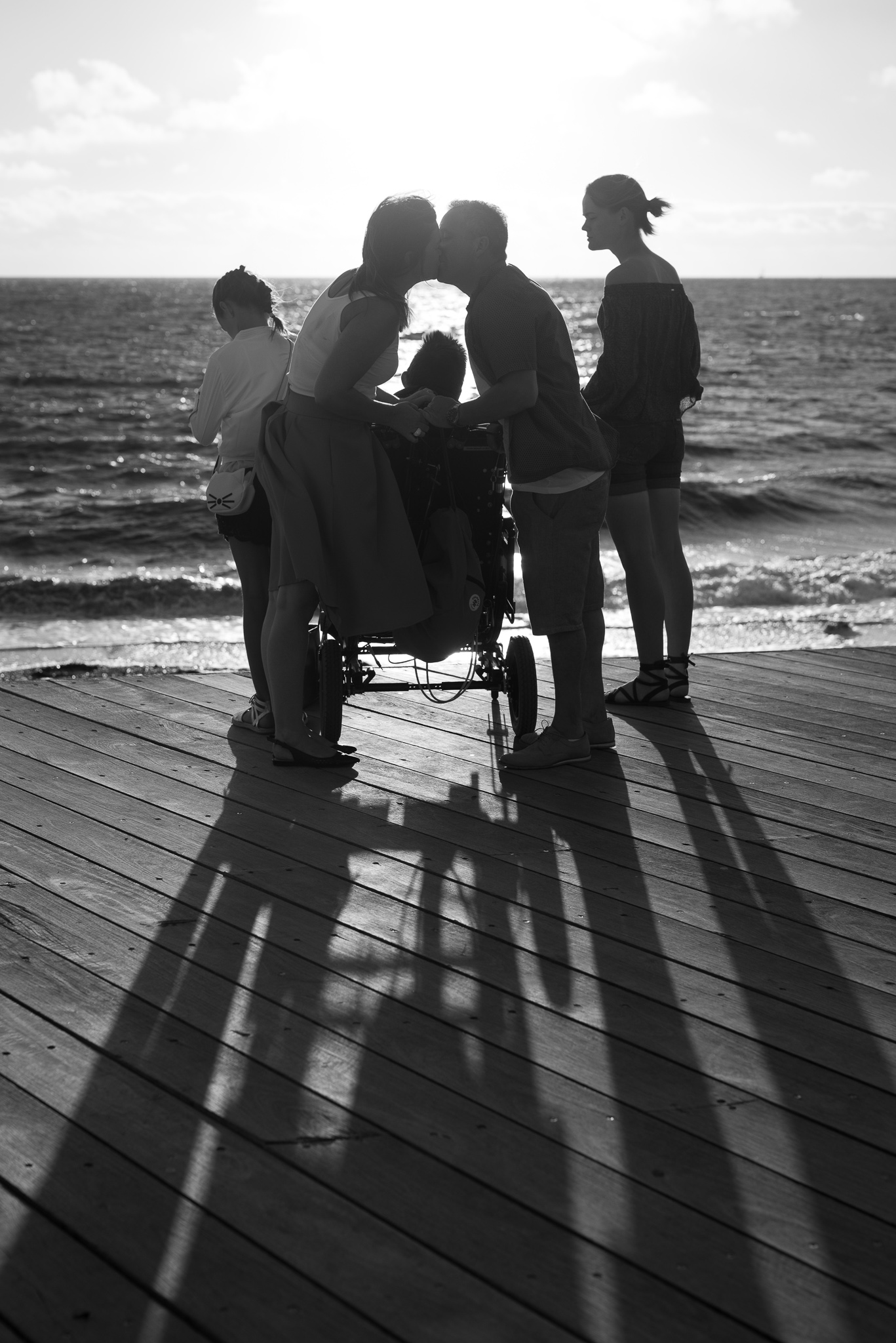 black and white silhouette of family photo with parents kissing over the kids heads