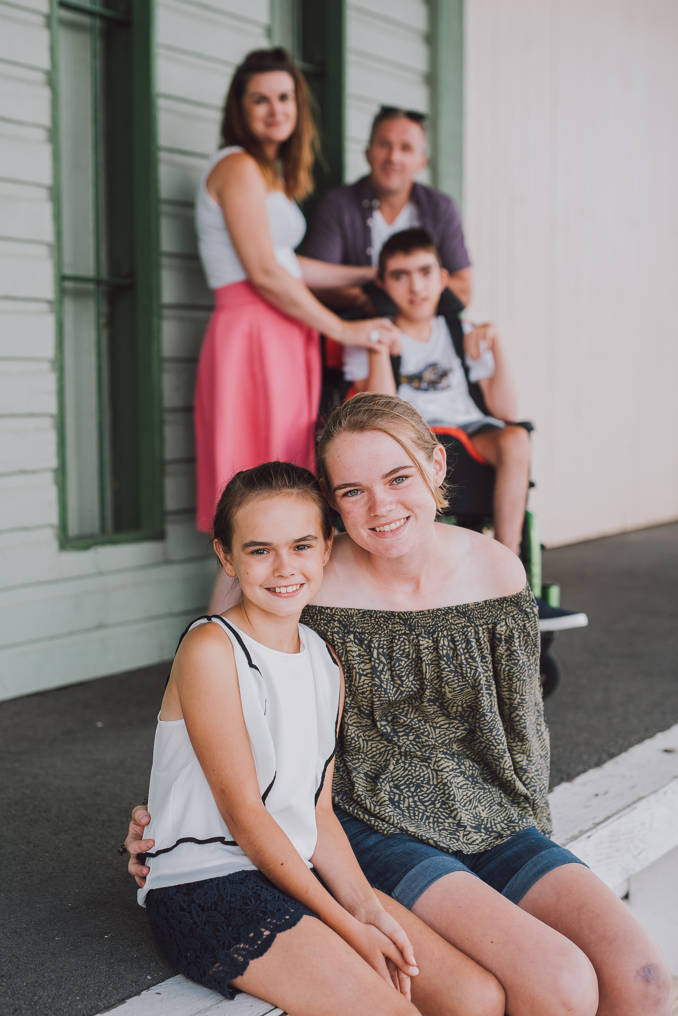 two girls having their picture taken in front of rest of family