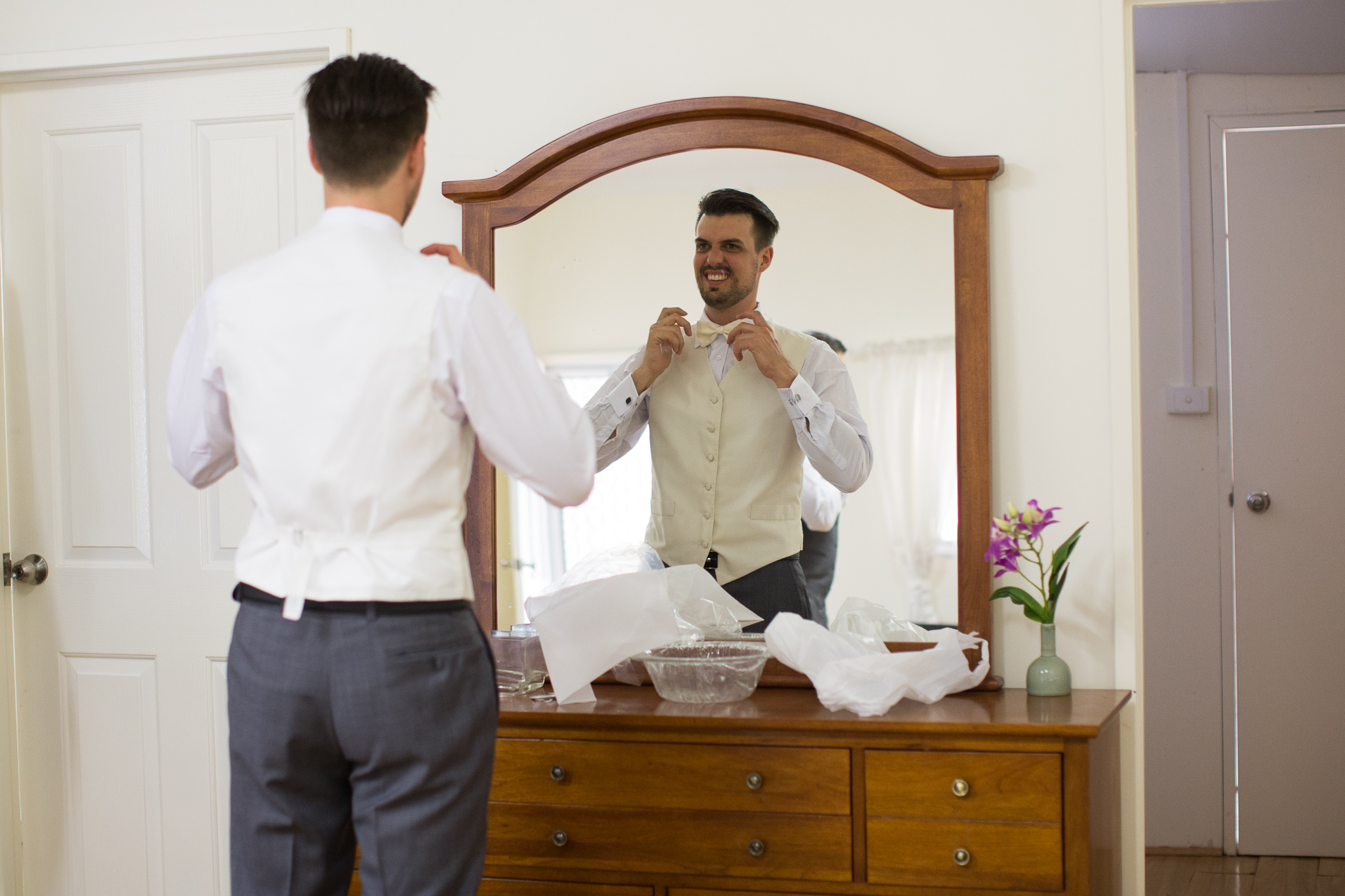 Groom fixes his tie getting ready at Serena Metta Retreat