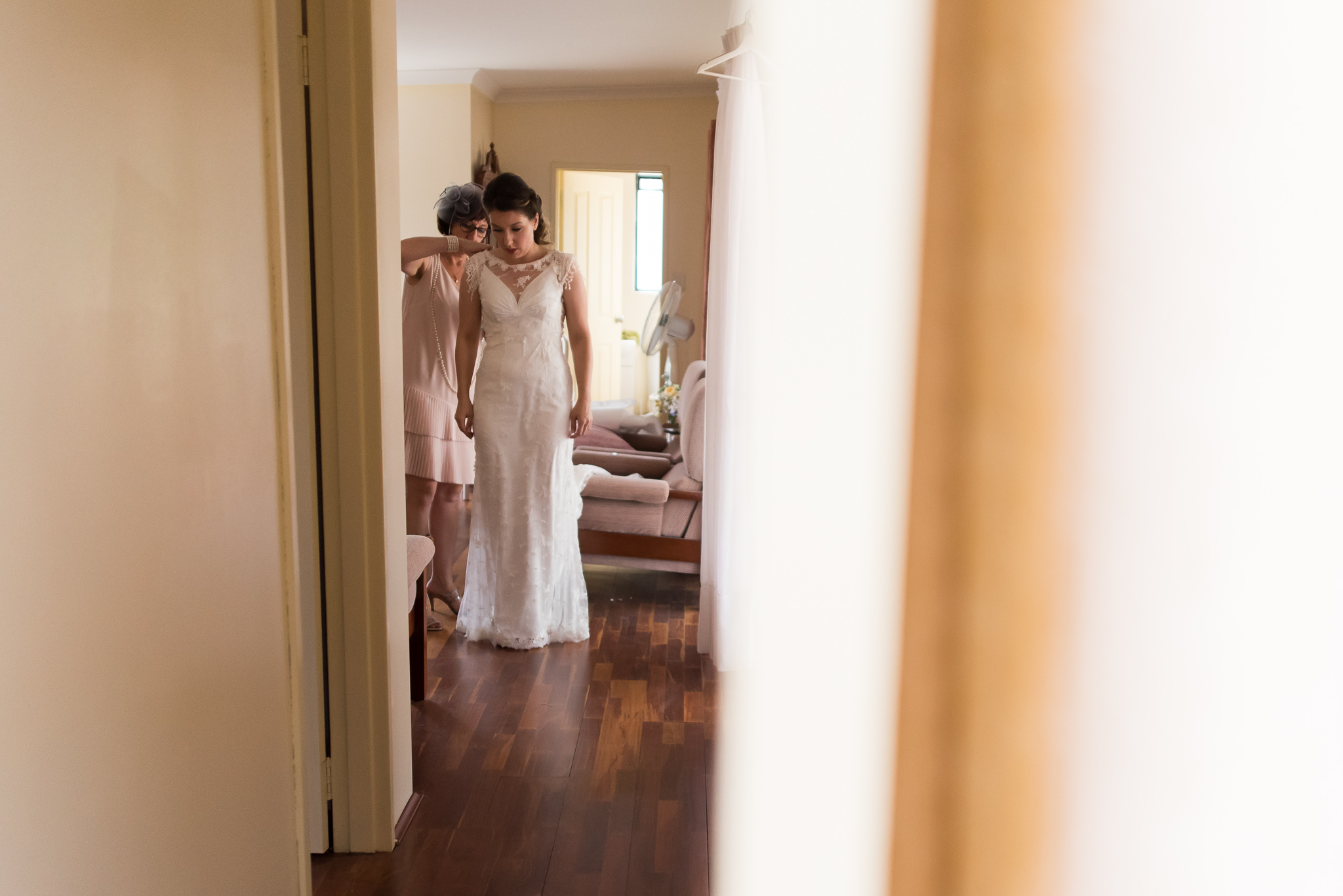 Bride's mother helps her do her dress