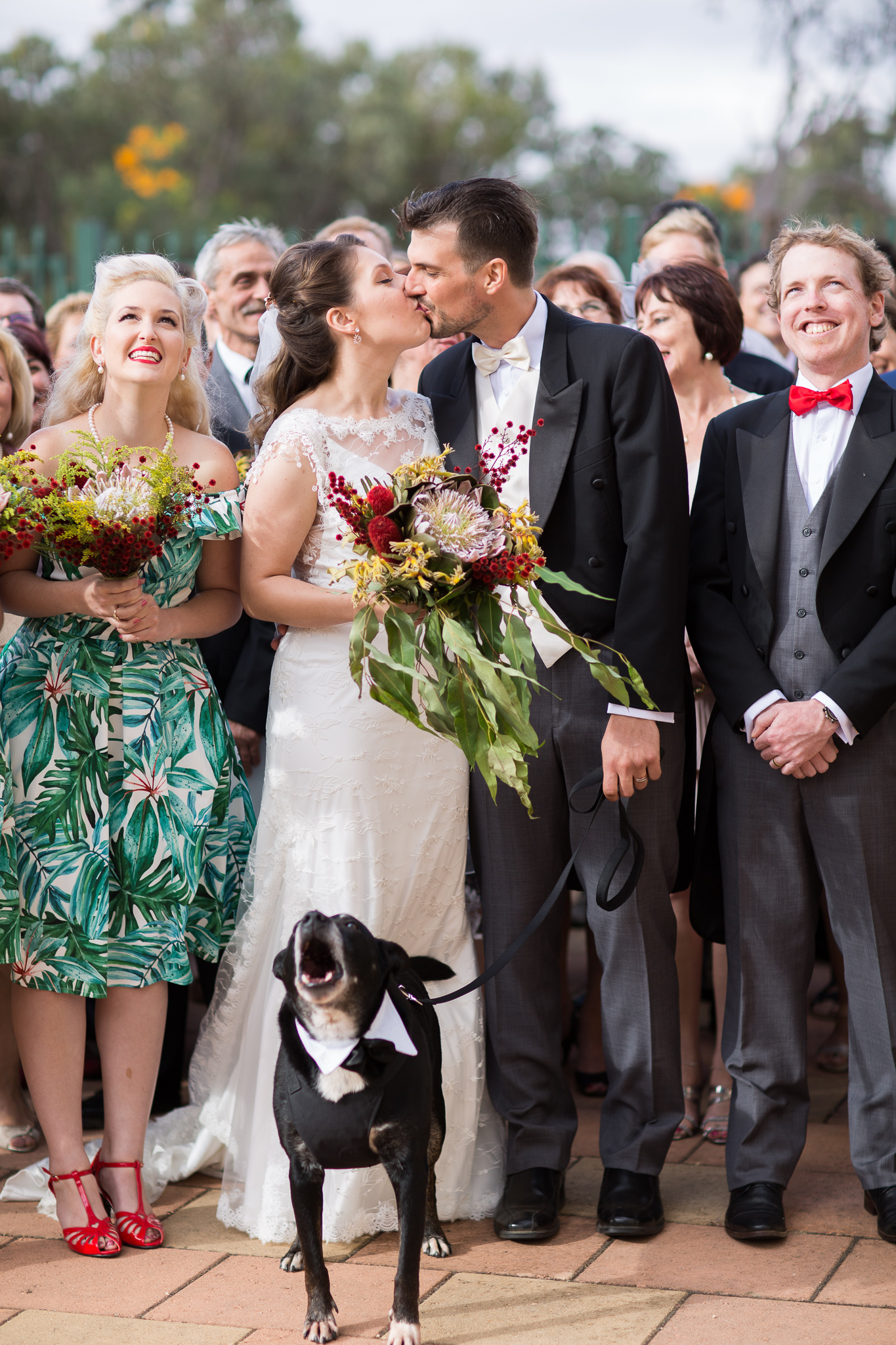 Wedding couple kiss during their family group shot