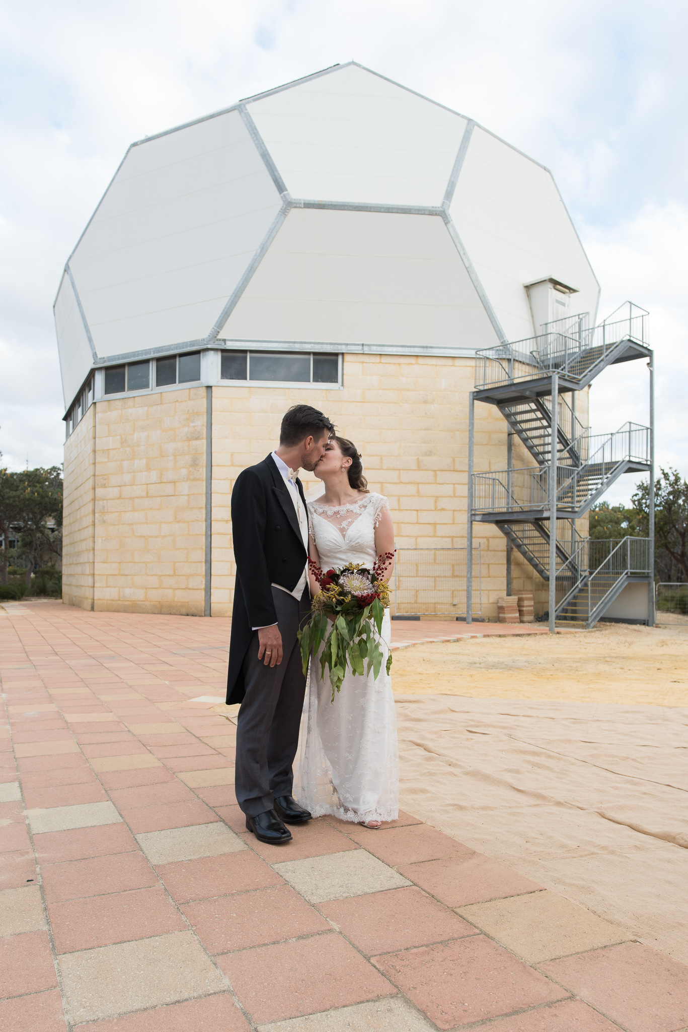 Bride and groom standing in front of observatory at Gin Gin