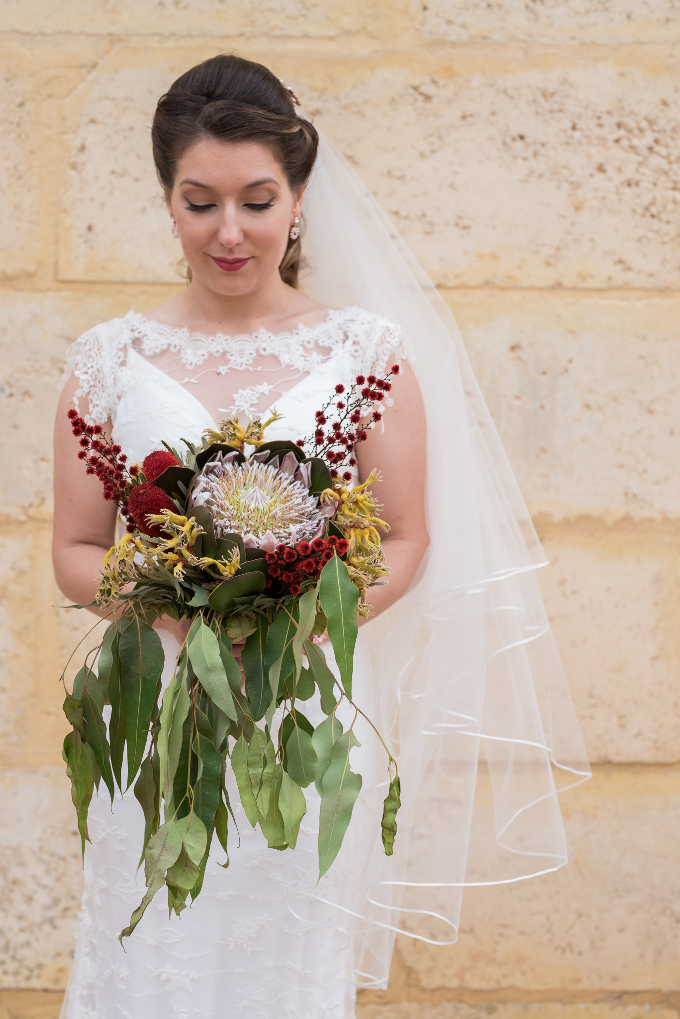 Bridal portrait looking down at her native wildflower bouquet