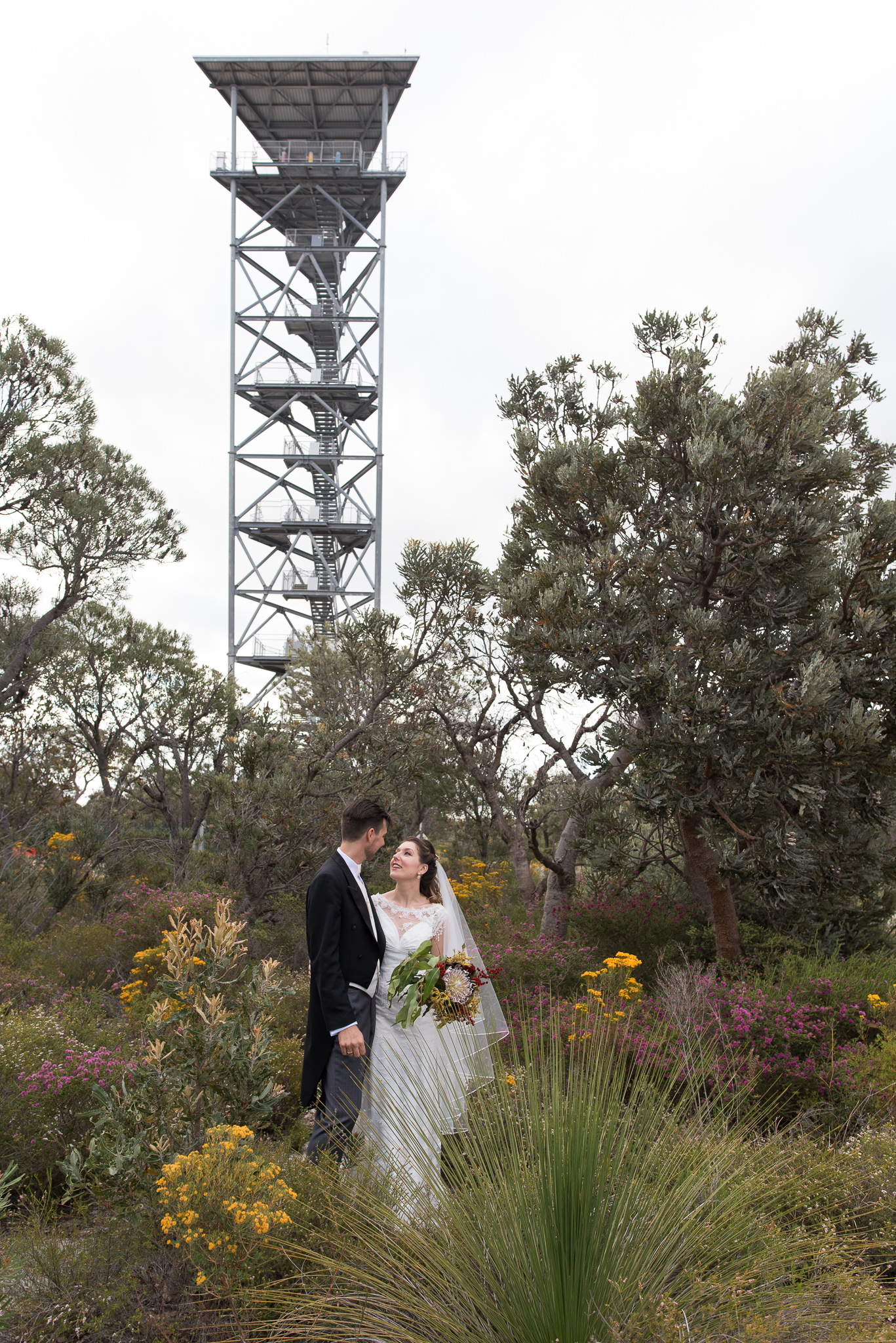 Bride and groom standing in the garden with the leaning gravity tower behind