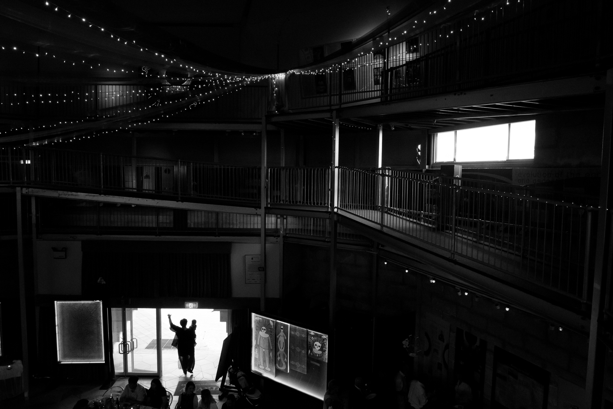 Silhouette of wedding guest holding child dancing in the reception doorway at GDC