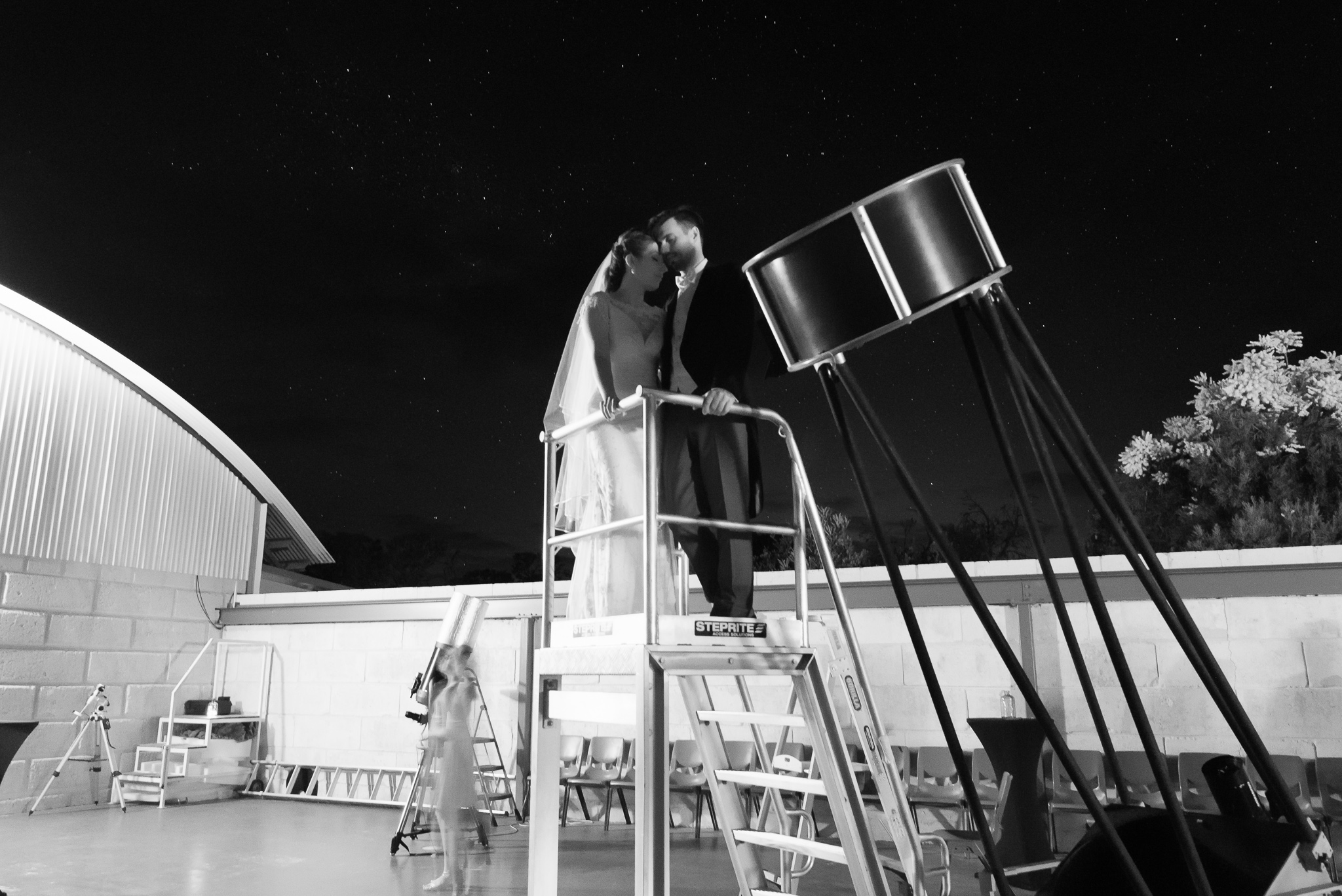 Observatory wedding couple standing near telescope under the stars in black and white