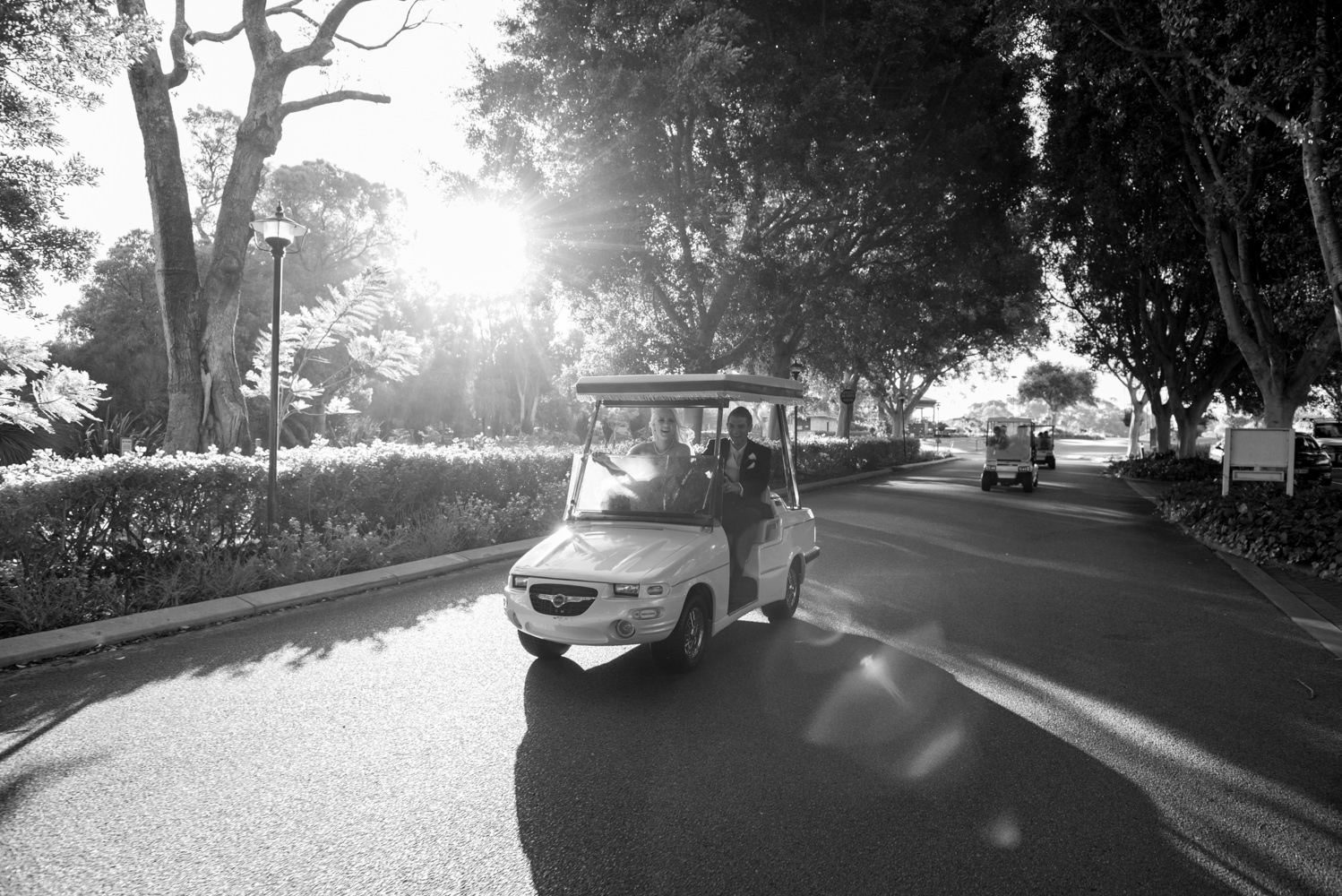 Black and white photo of bridal party driving golf carts to Joondalup resort reception