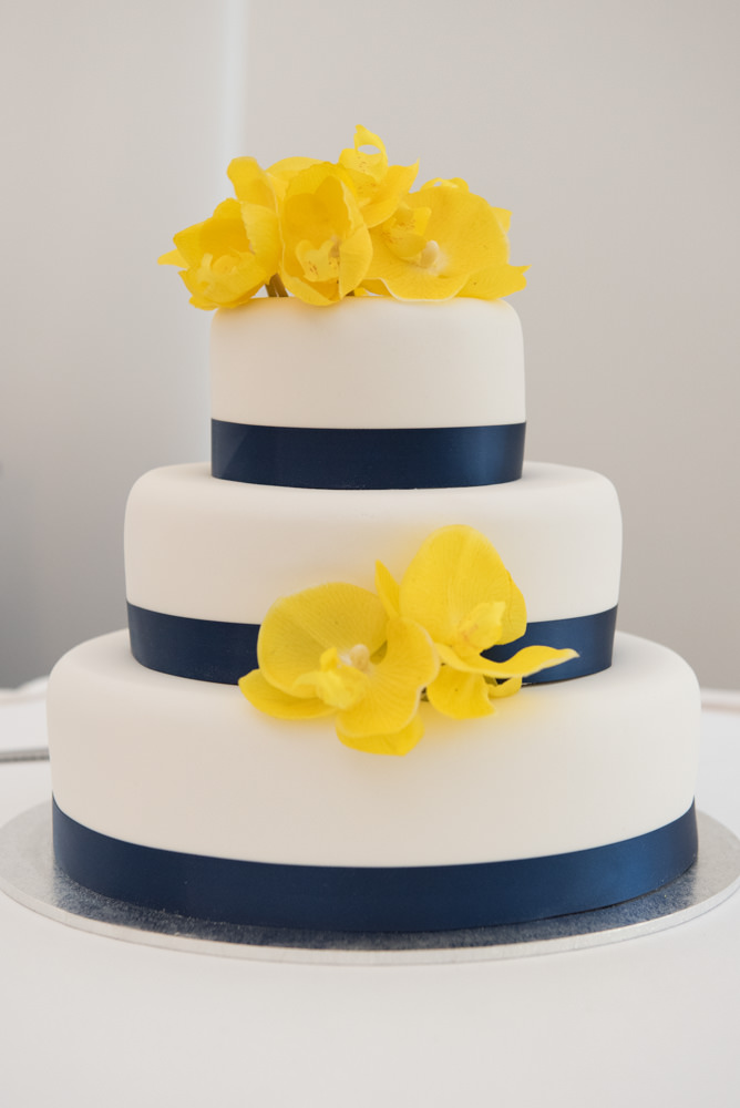 Wedding cake with yellow flowers and blue ribbon