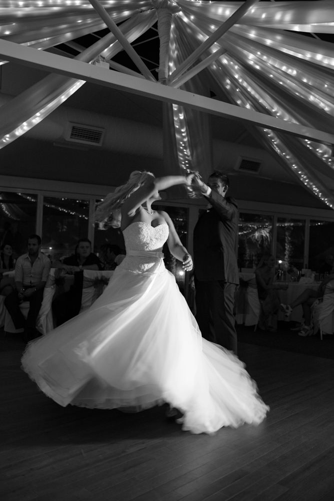 Black and white photo of bride and groom dancing, spinning on the dance floor