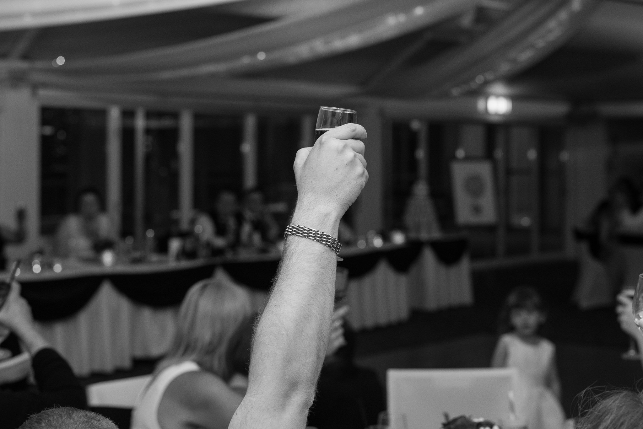 wedding guest holding up a drink toasting during wedding speech