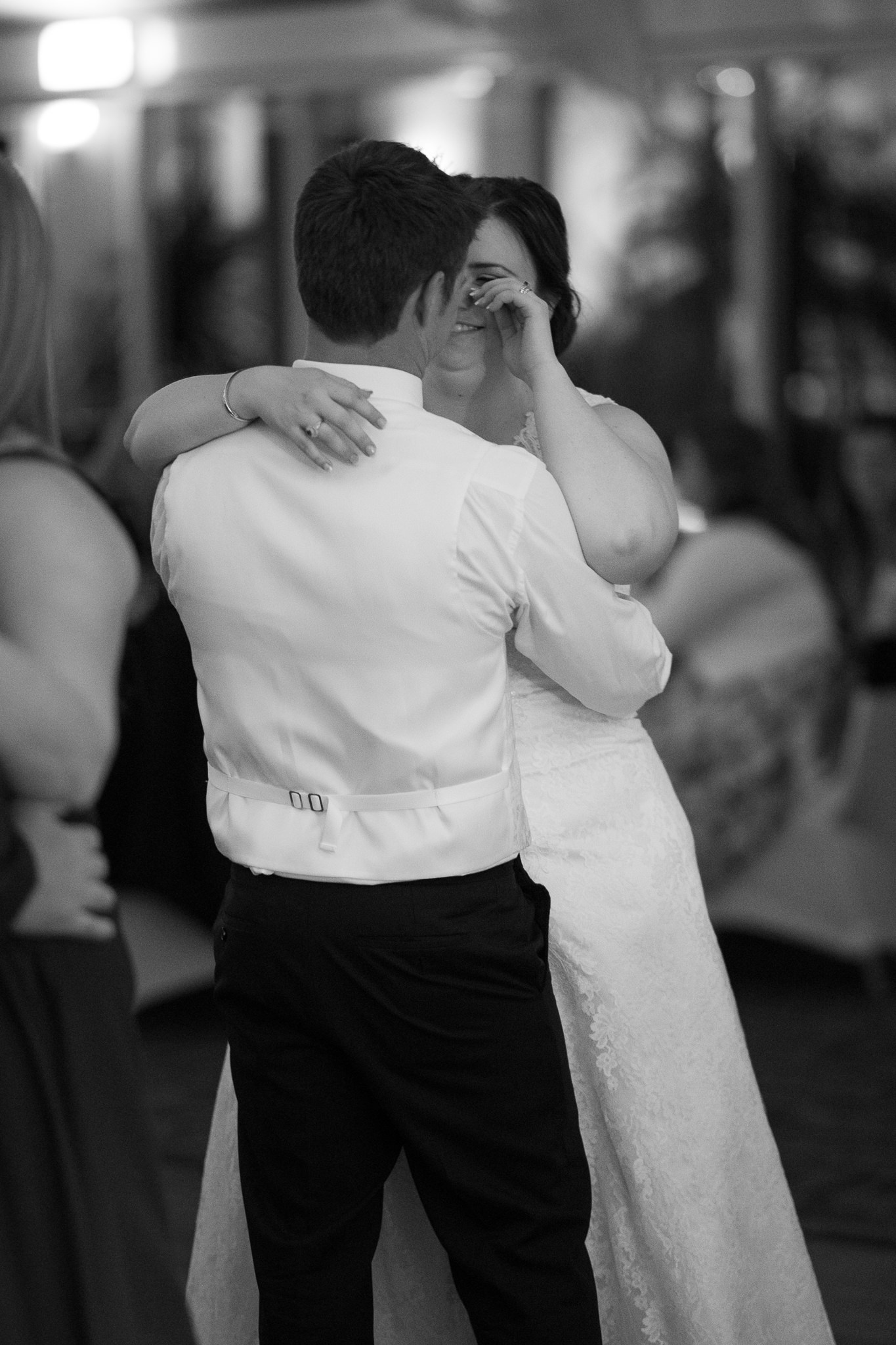 bride wiping tear away while she dances with her groom