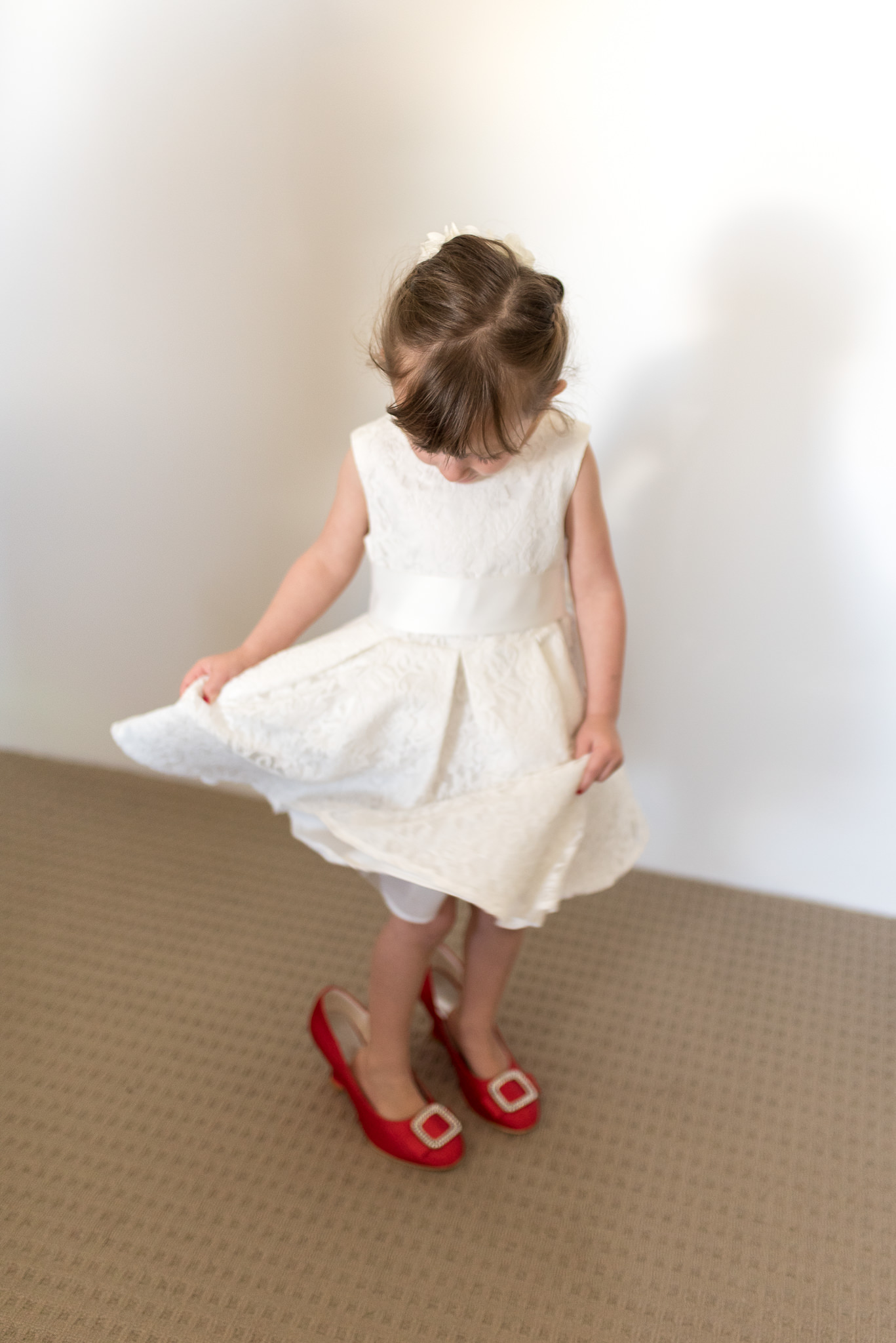 flower girl tries on bride's red wedding shoes