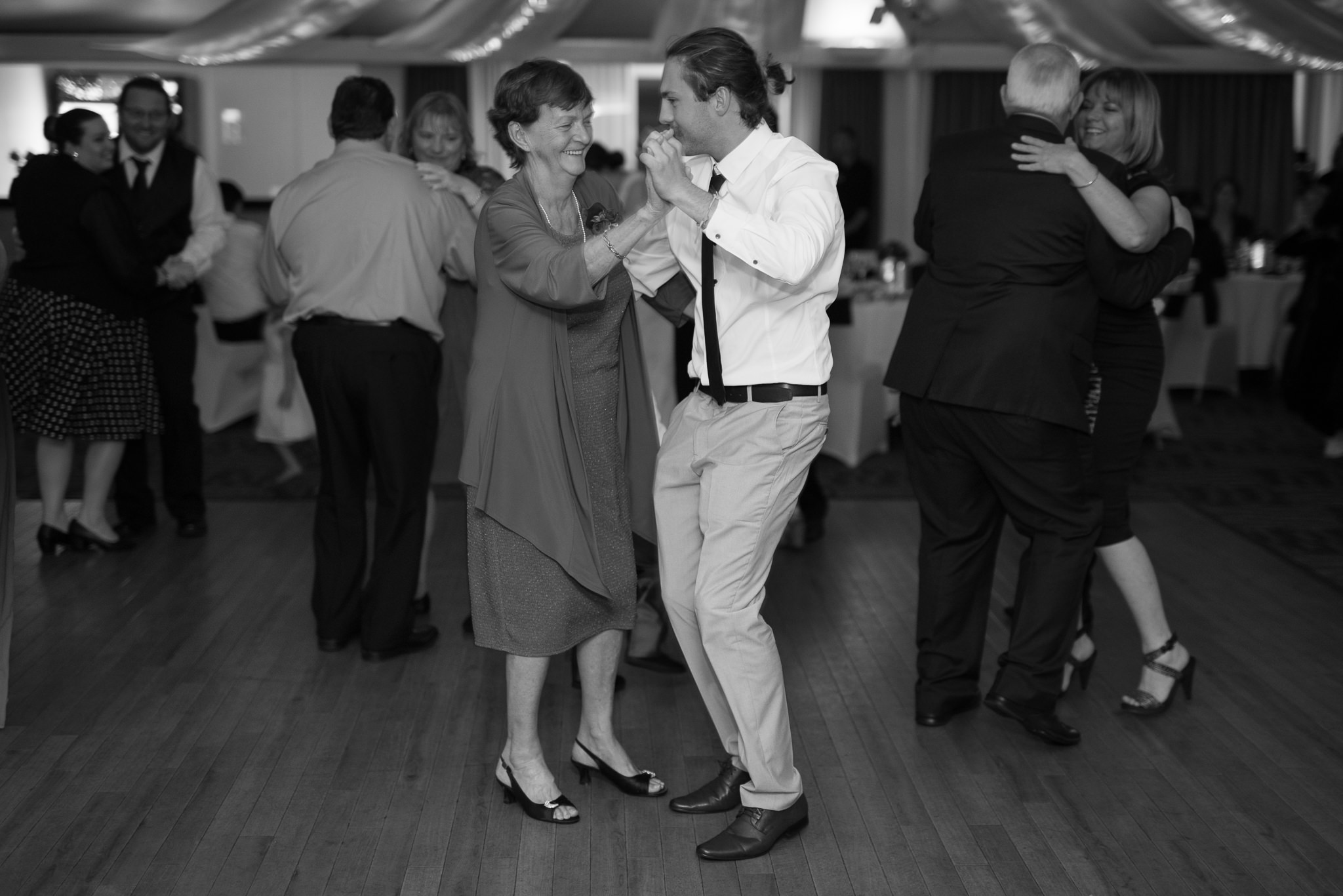 young funky wedding guest dancing with elderly lady at wedding reception