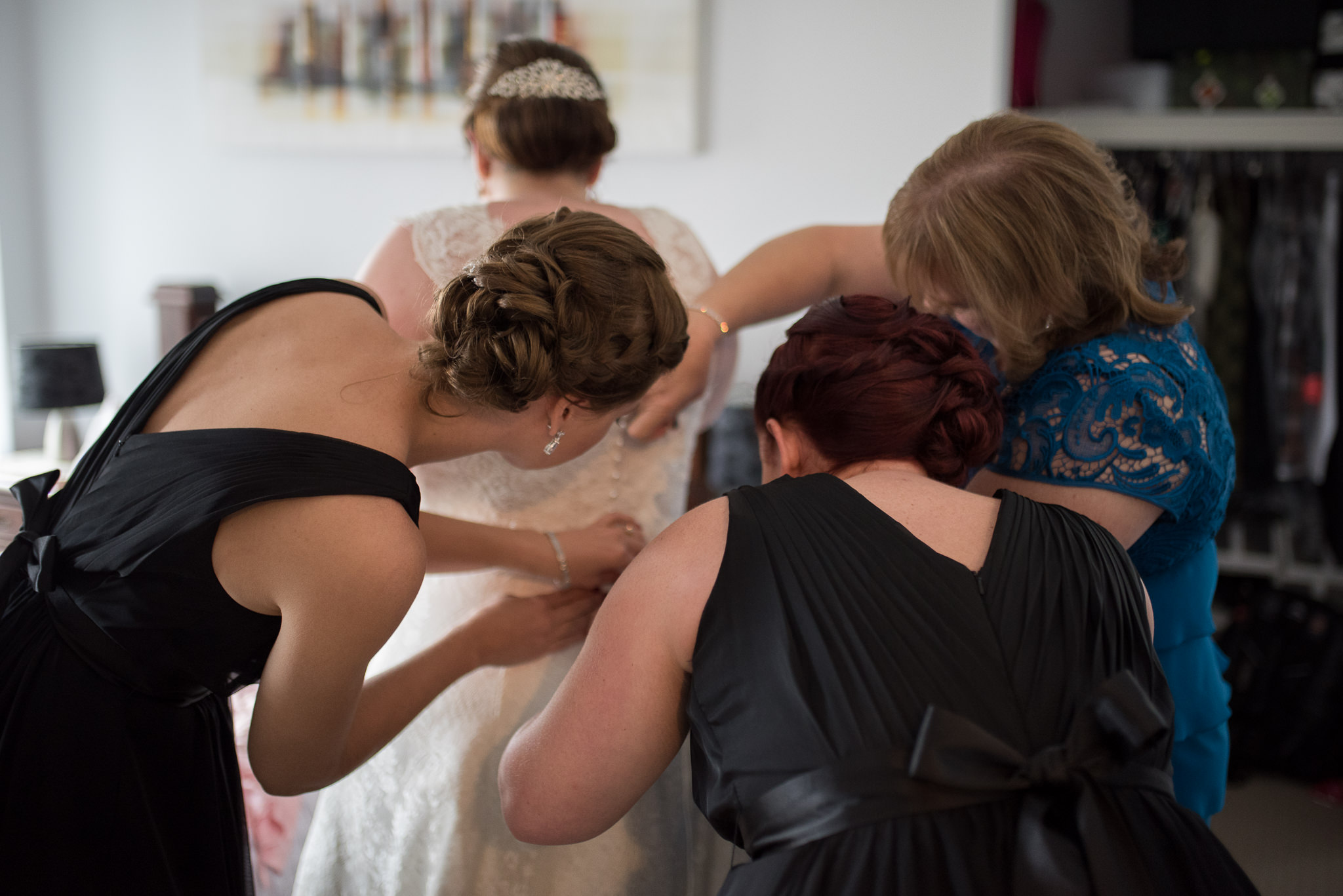 bride having her dress buttons done