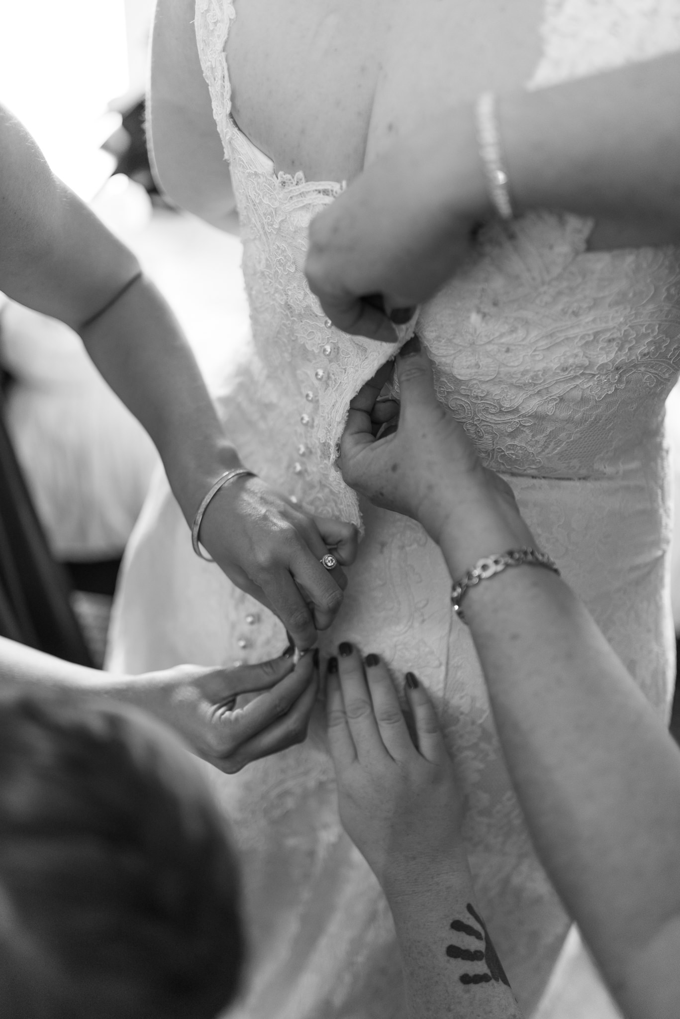 bridesmaids help do wedding dress buttons