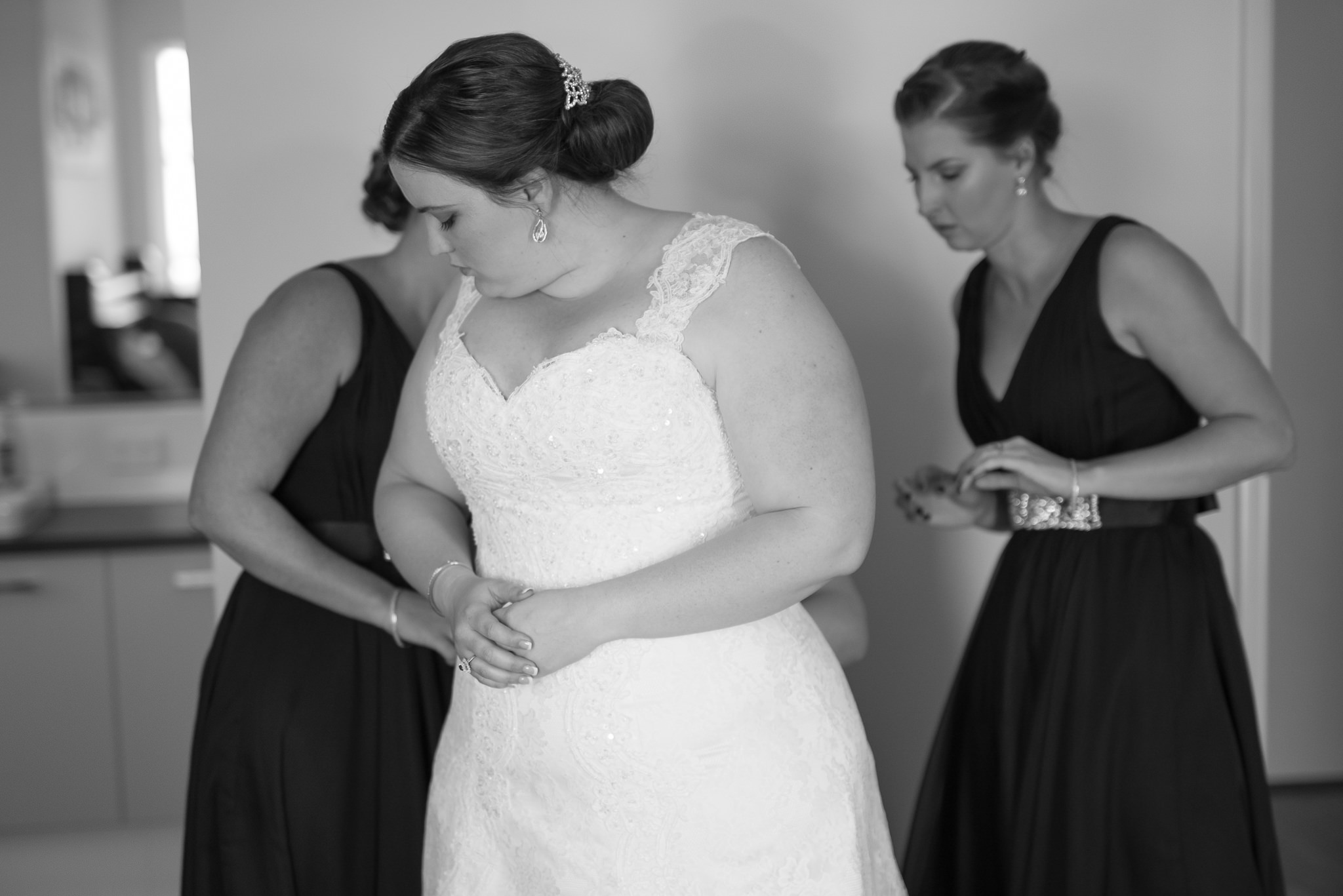 bride looks elegantly to the side putting her dress on