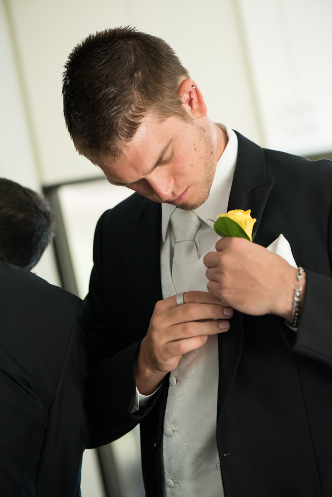 Groom pinning button hole to his jacket