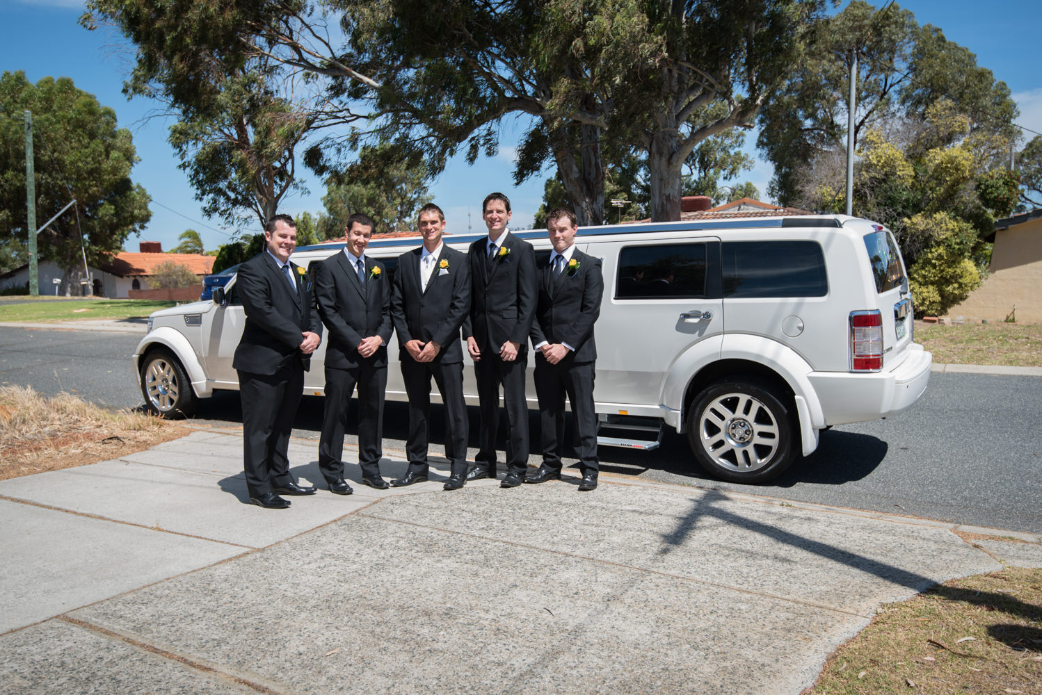 Groom and groomsmen waiting with their limousine