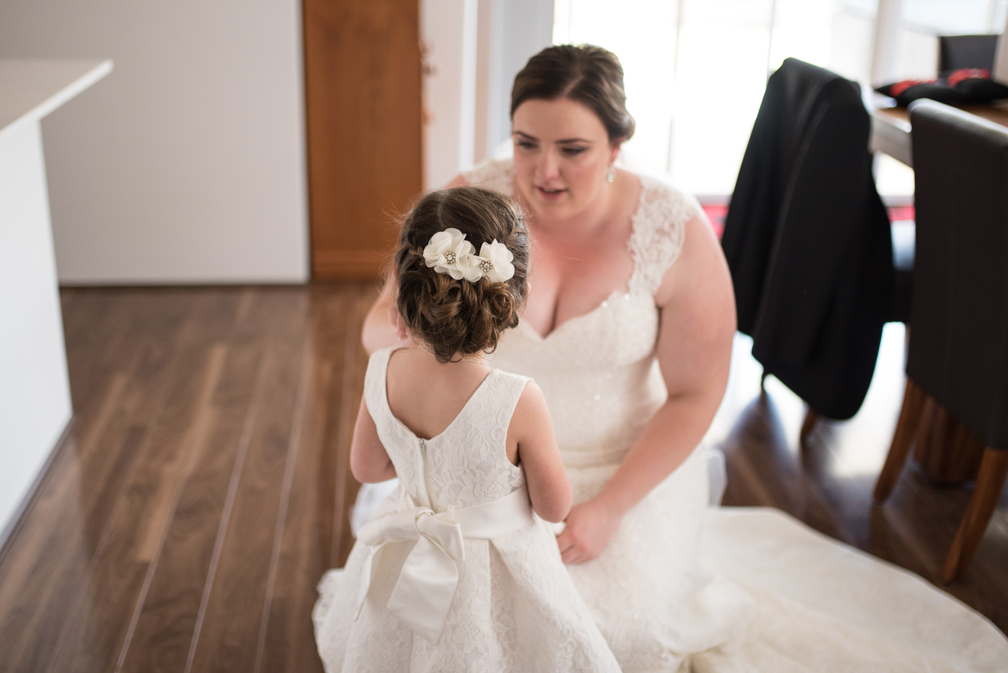 bride crouches down and talks to little flower girl