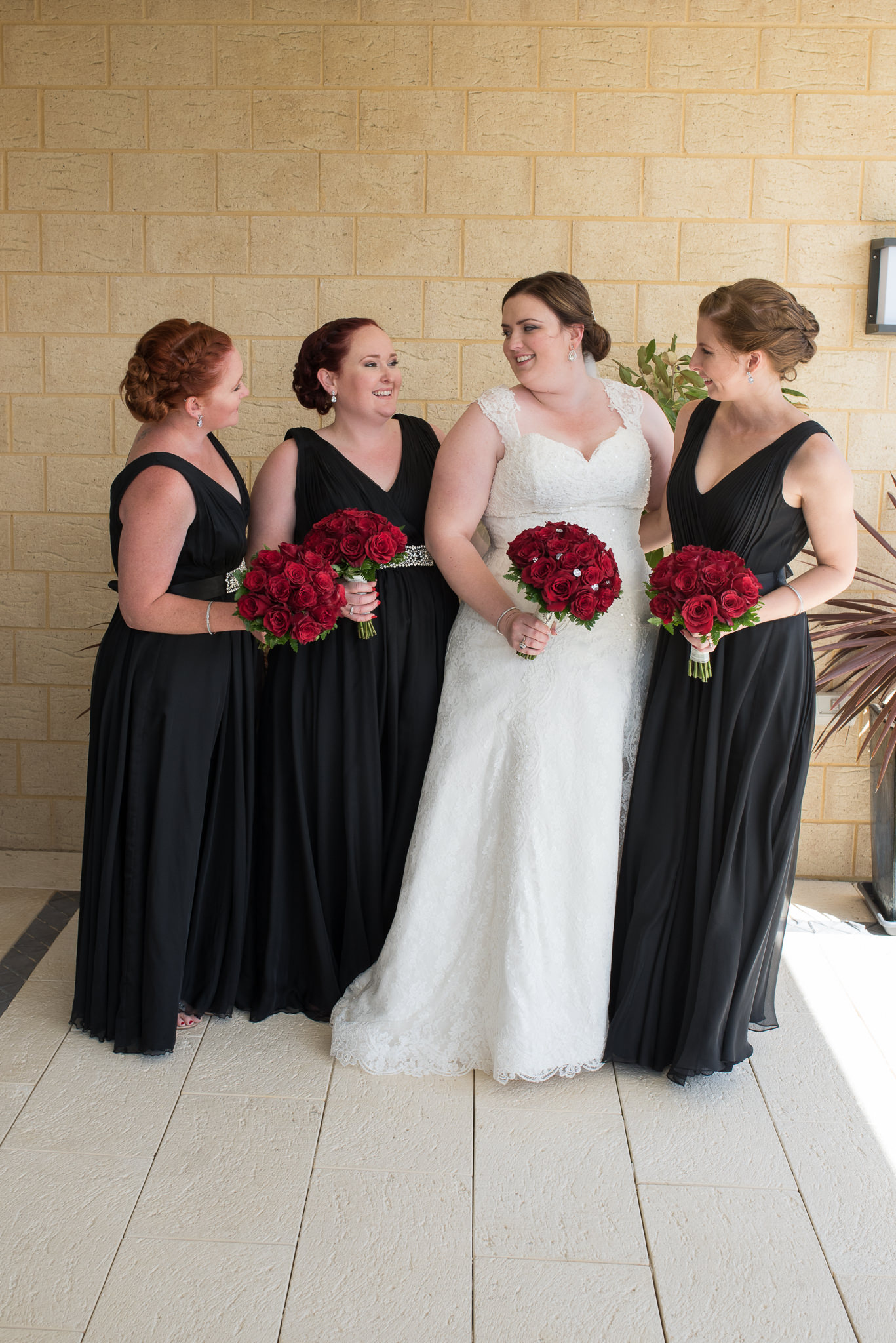 Bride and bridesmaids in black dresses looking at each other