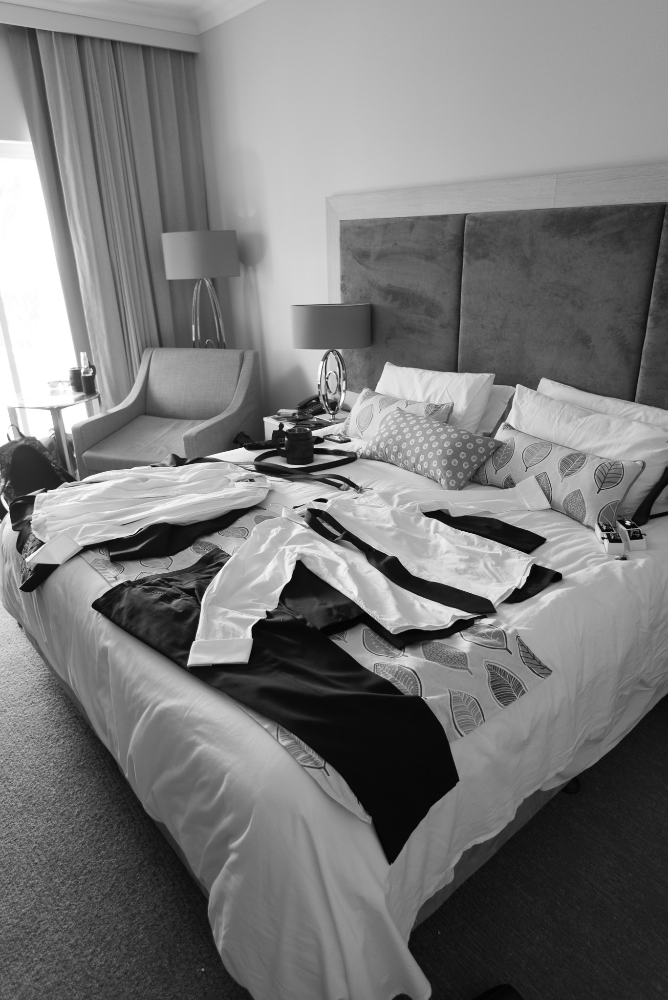 groom's clothes laid out on the bed in black and white