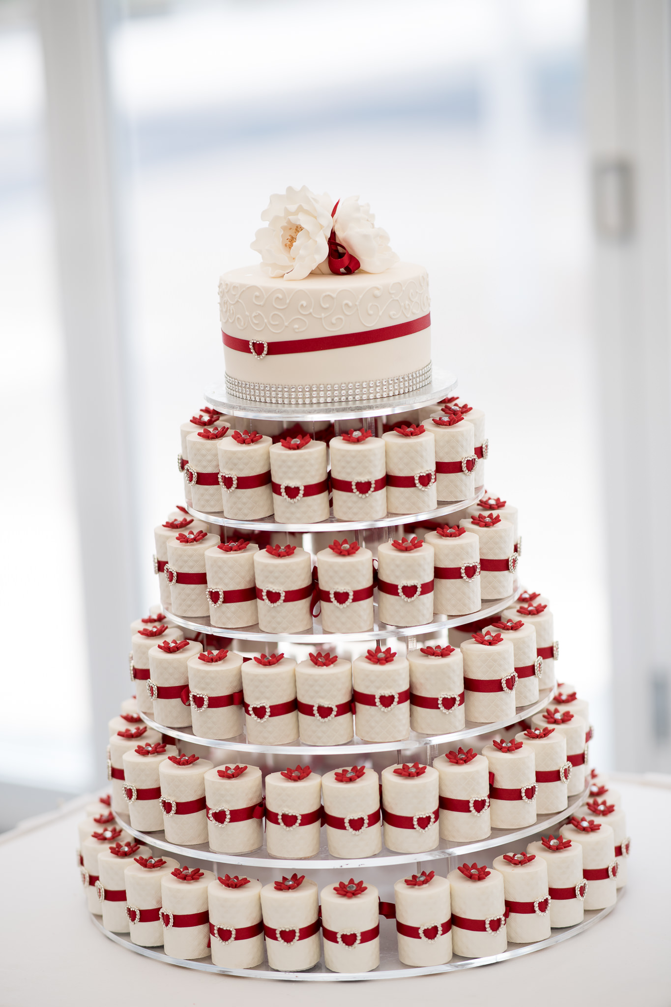 white wedding cupcake tower with red ribbons