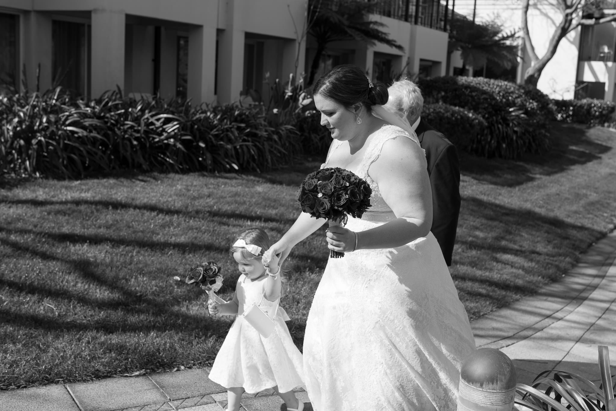 bride walks the little flower girl towards wedding ceremony