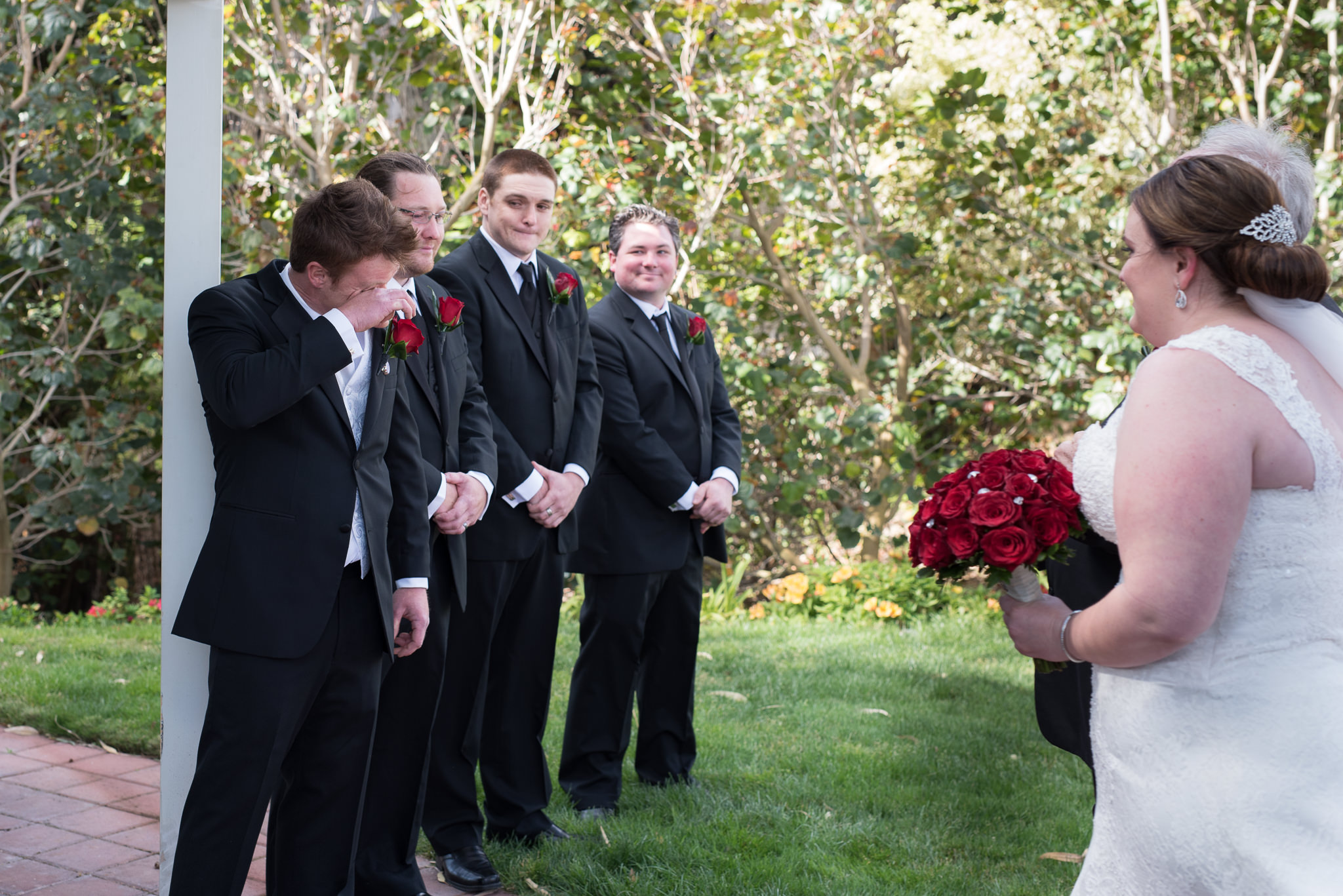 groom wipes a tear away as his bride approaches