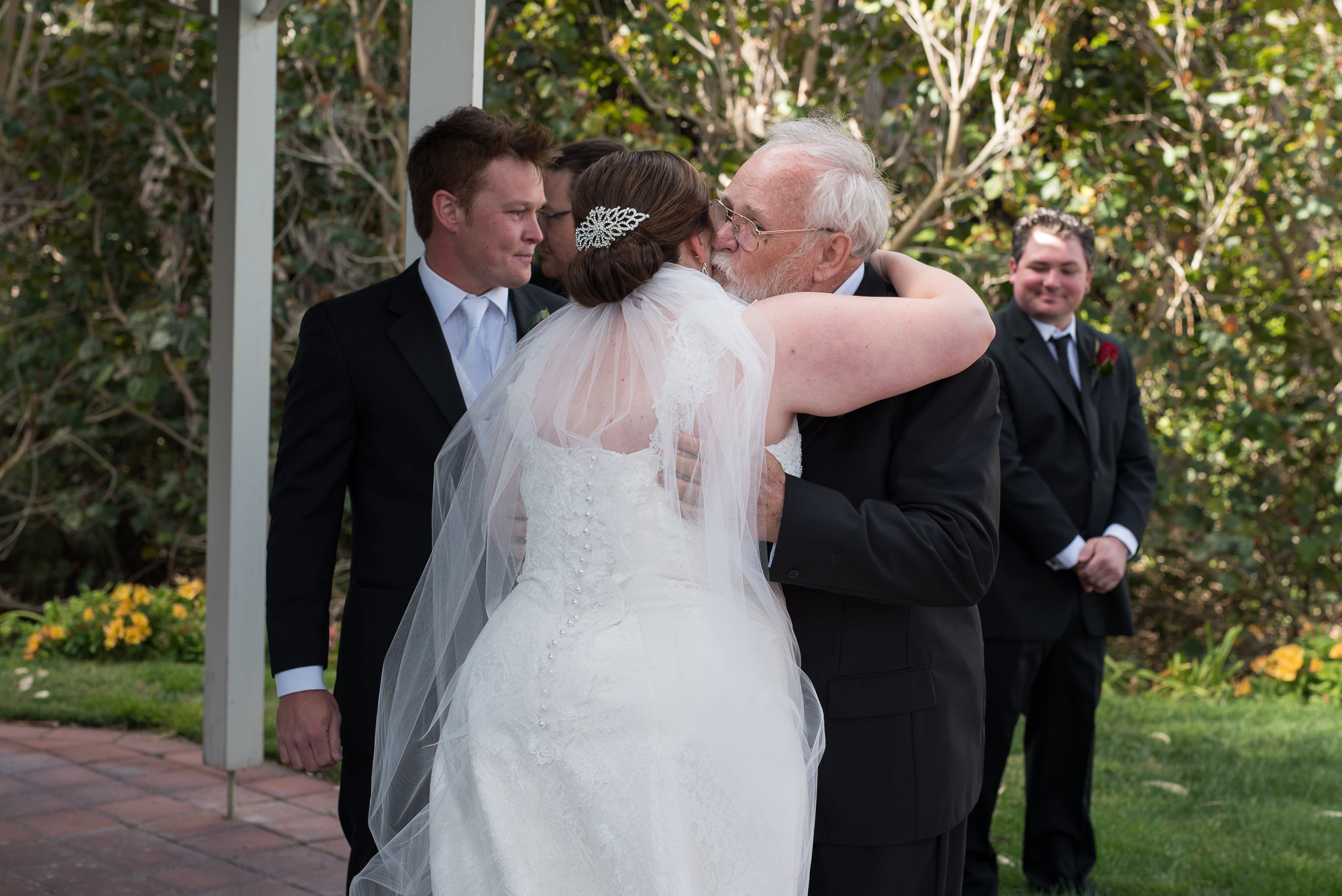 father of the bride kisses her as he gives her away