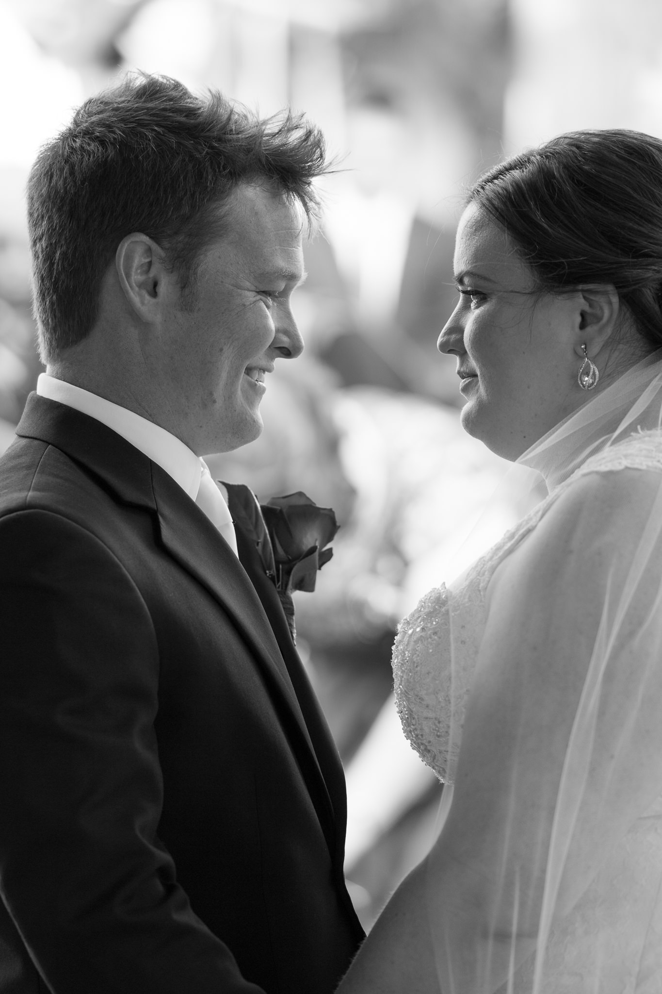 groom smiles at bride in black and white