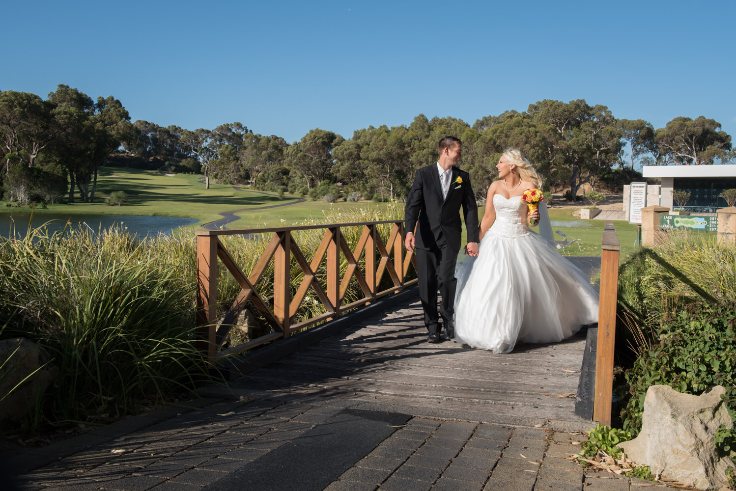 Bride and groom walking across the bridge at Joondalup golf course