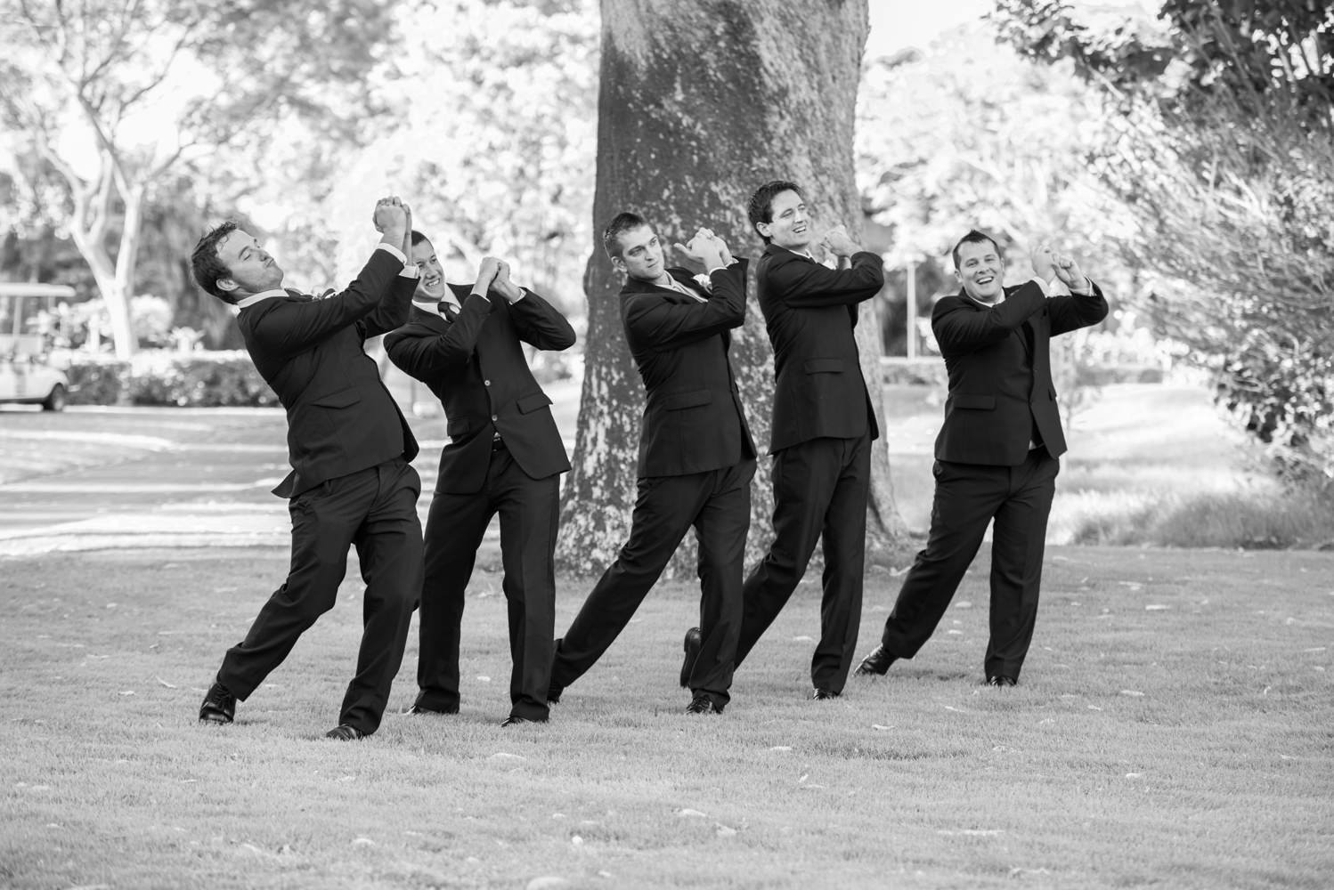 Groom and groomsmen swinging invisible golf clubs