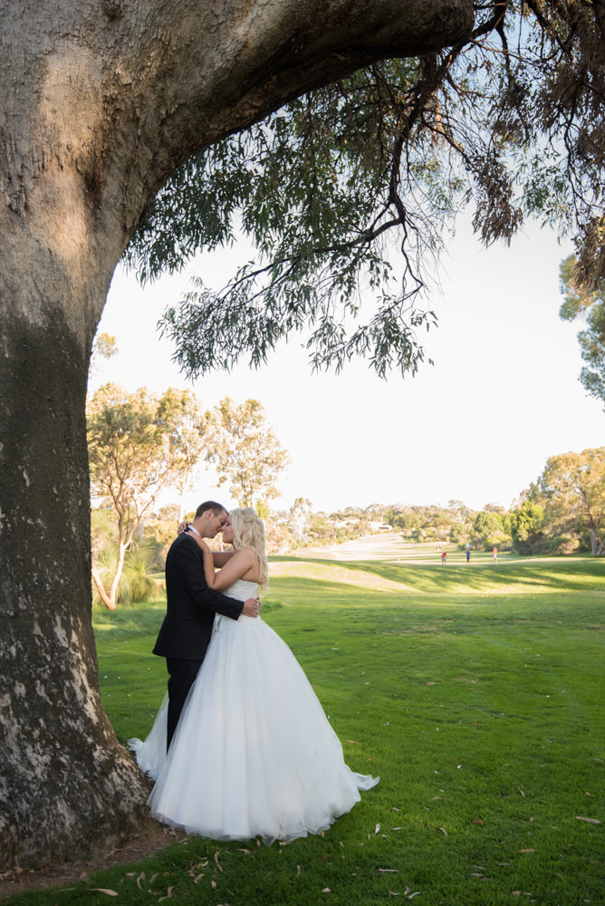 Bride and groom cuddling on Joondalup golf course under tree