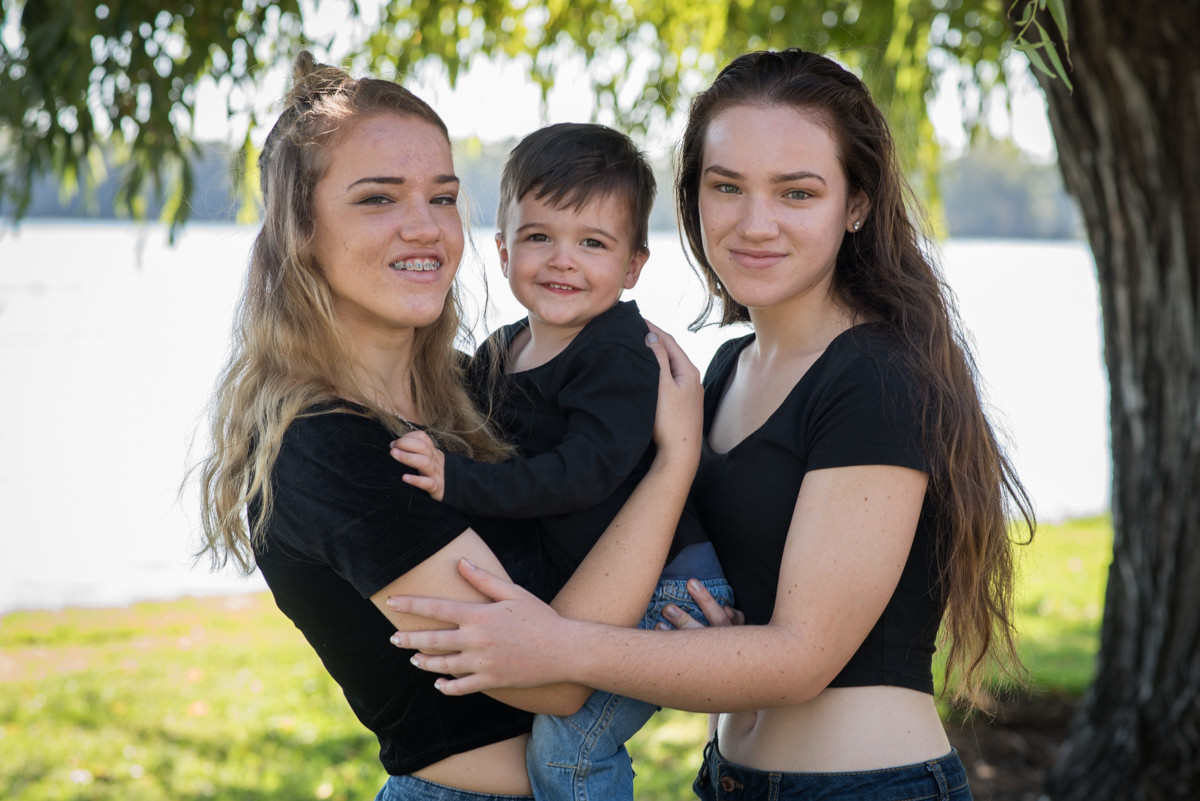 Two girl sisters holding their little boy cousin at Lake Monger