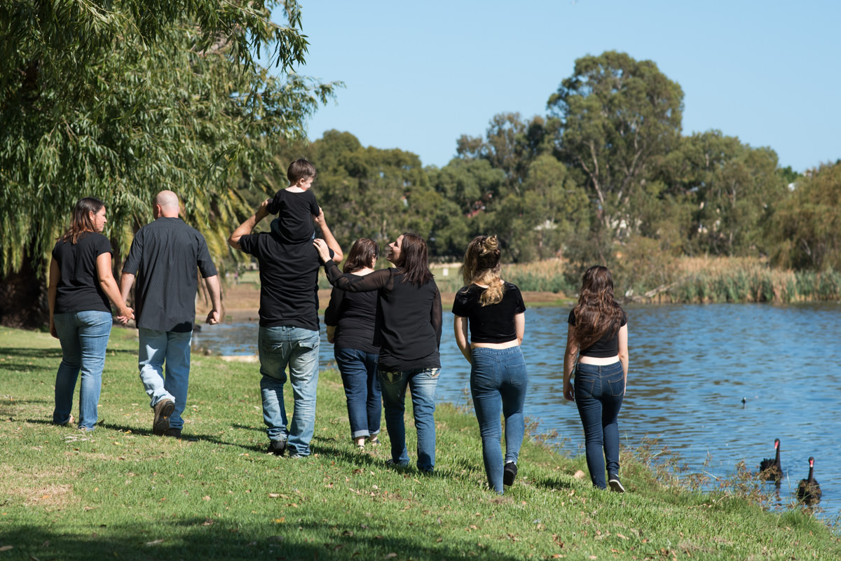 Family in Black shirts and blue jeans walking along the edge of Lake Monger