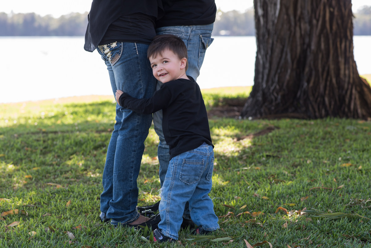 Little boy hugging his parents legs by Kruger Photography