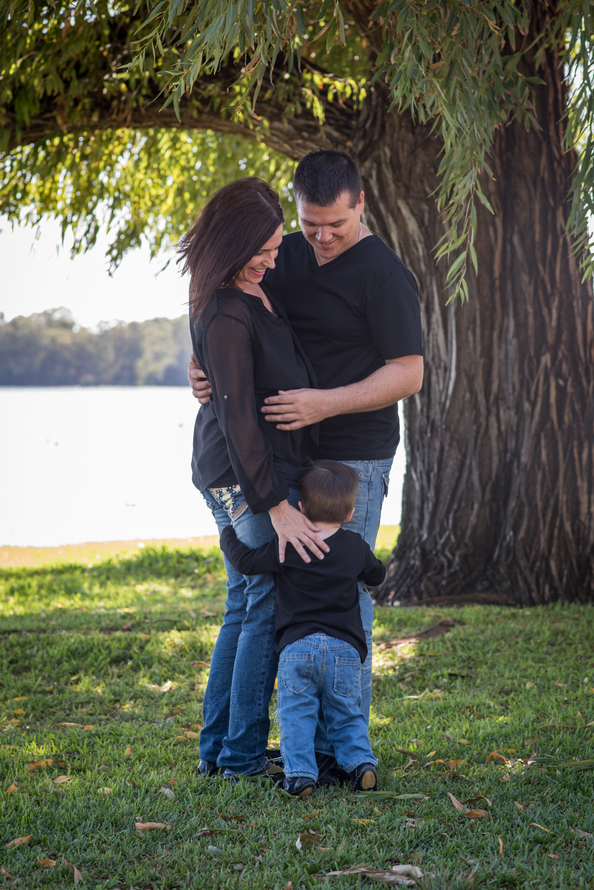 Parents looking down at their little boy hugging their legs