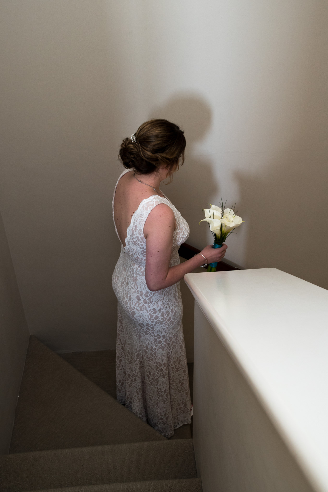 Bride holds her bouquet and walks down the staircase of her villa at Mindarie Marina