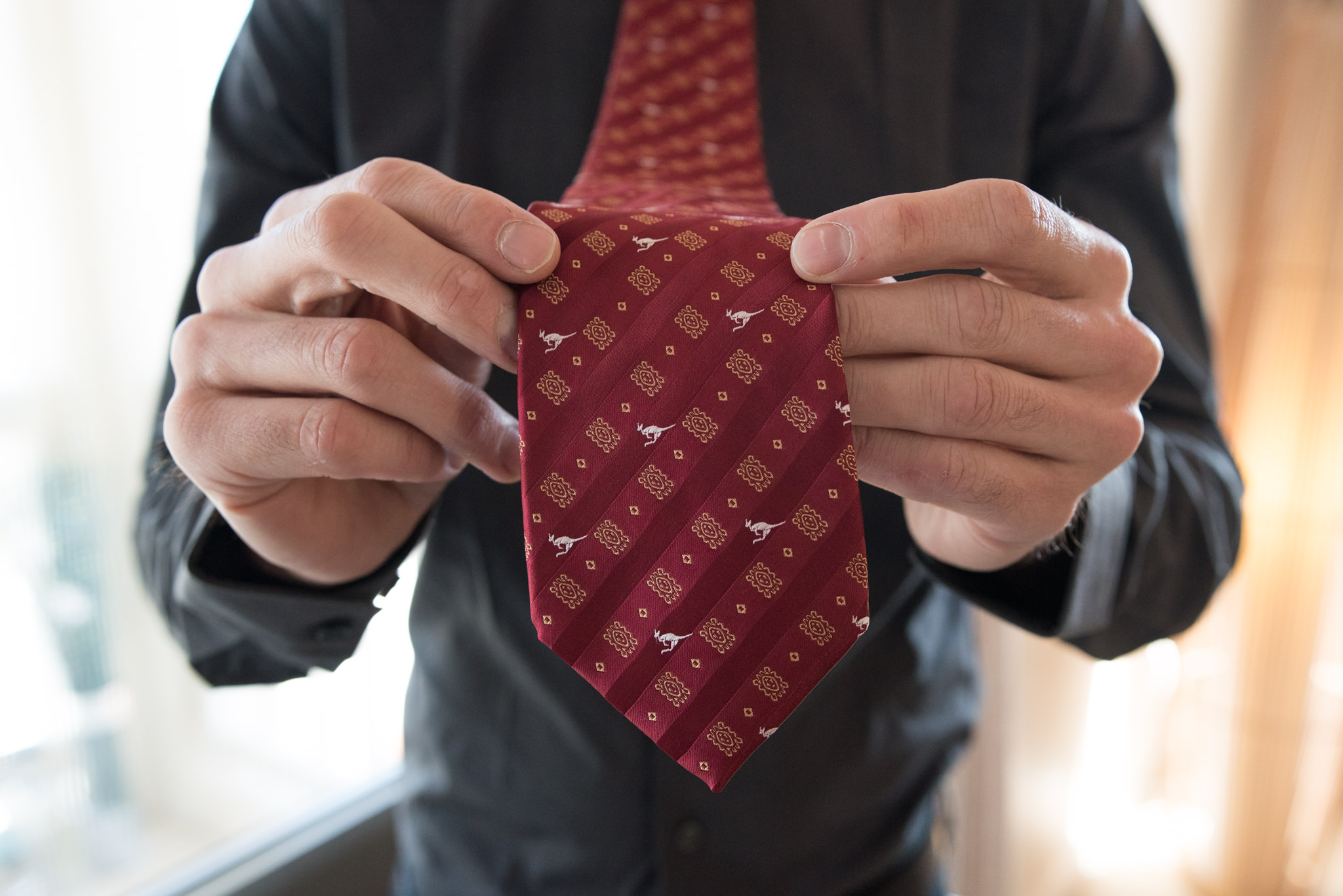 Close up of groom holding his tie with little kangaroos on it